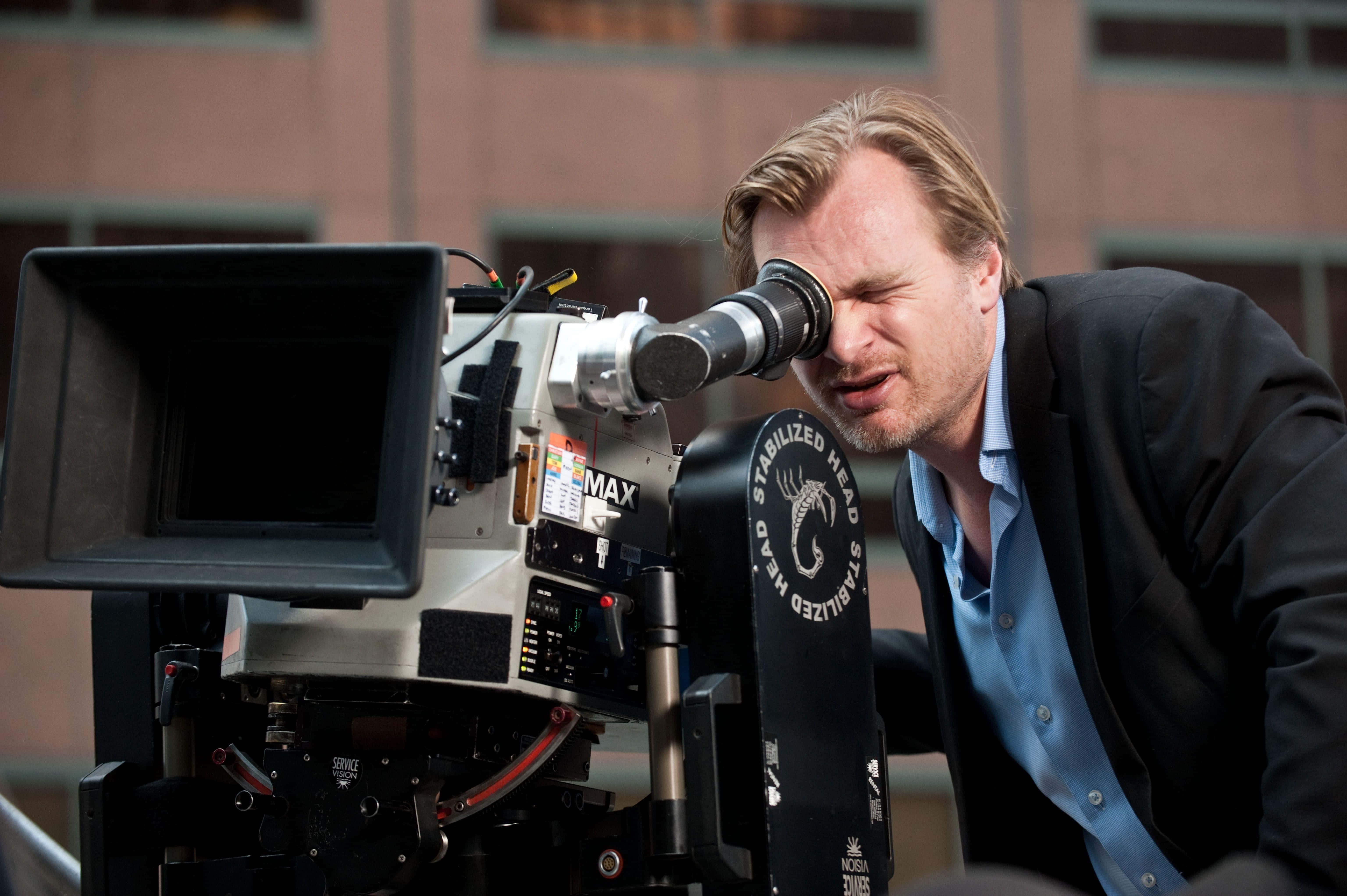 Christopher Nolan 桌布 壁紙 — 一位電影製作人在白天透過城市天台上的大型專業電影攝影機專注地凝視。