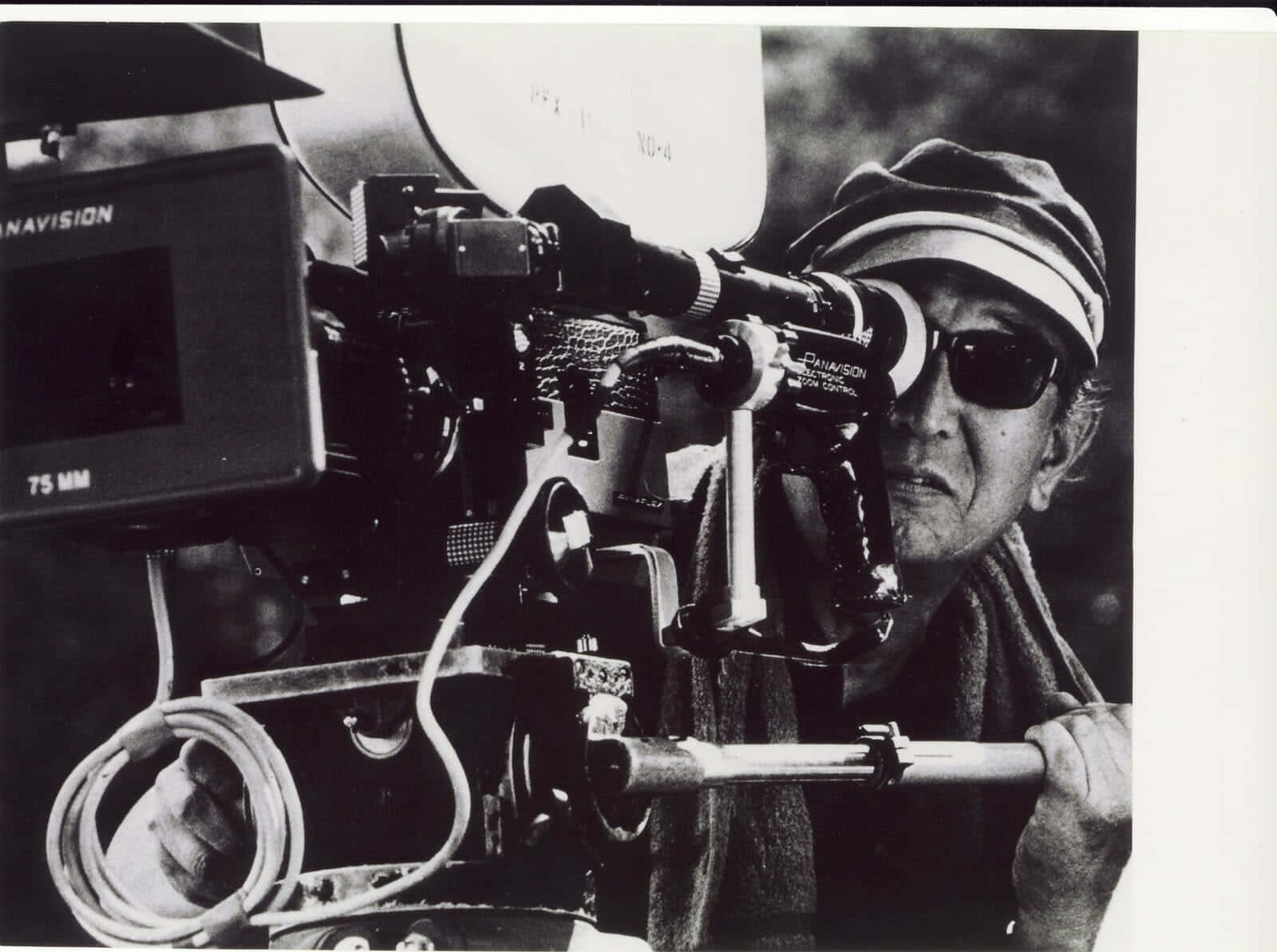 Akira Kurosawa 桌布 壁紙 — 一位電影製作人專注操作配備75mm鏡頭的大型電影攝影機的黑白特寫。