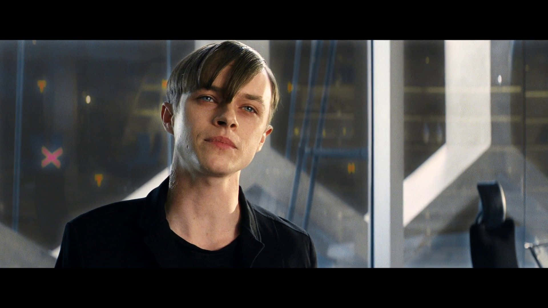 Harry Osborn 桌布 壁紙 — 一位頭髮向後梳的年輕男子，在一個光線昏暗、帶有玻璃牆和幾何陰影的現代室內空間中，專注地凝視前方。
