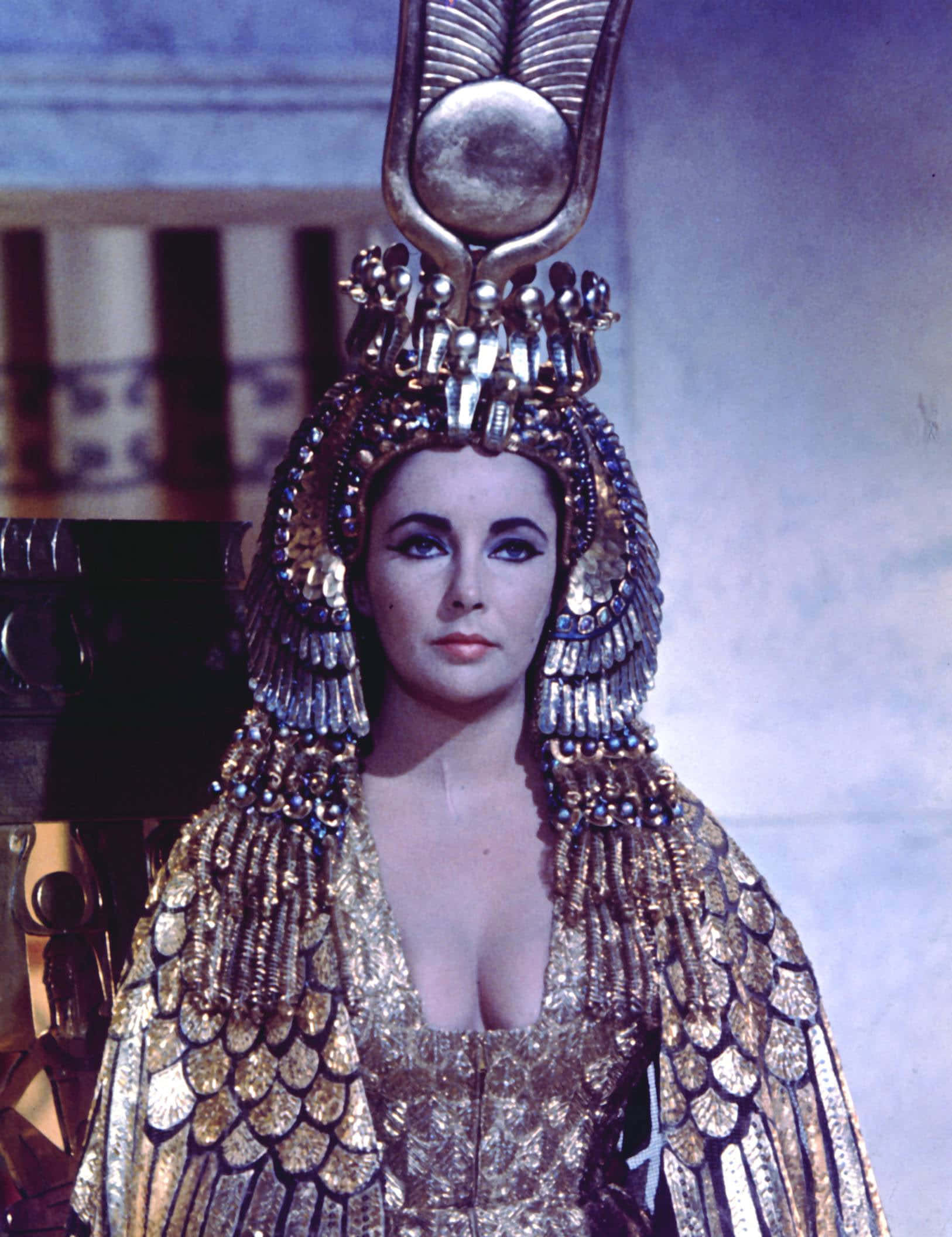 Cleopatra 桌布 壁紙 — 一位高貴的女性，戴著華麗的金色埃及頭飾，身穿鱗片圖案的長袍，以銳利的眼神凝視前方。