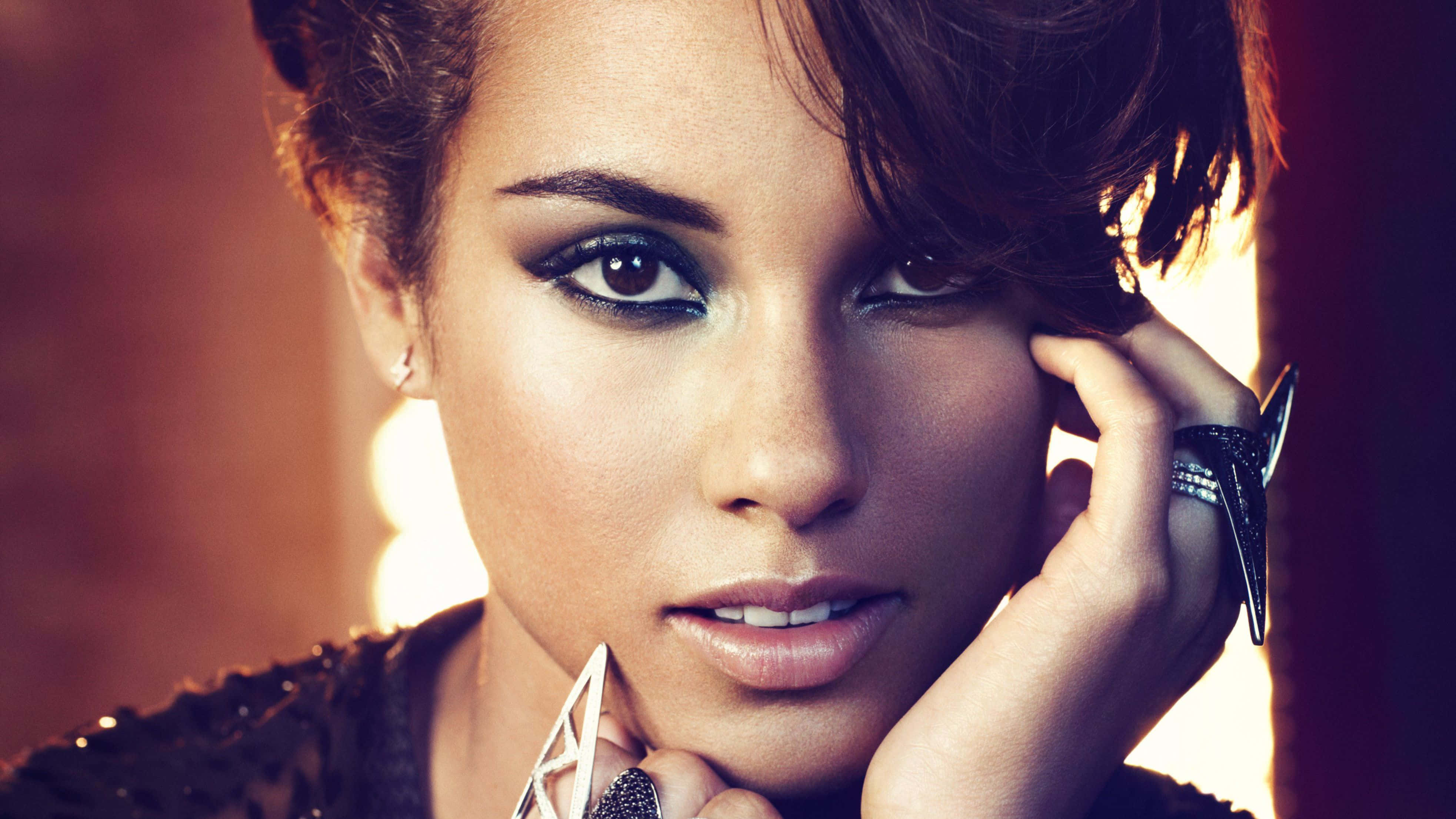 Alicia Keys 桌布 壁紙 — 一位魅力四射的女性，妝容大膽，短黑髮，托腮凝視，手上戴著一枚大戒指。