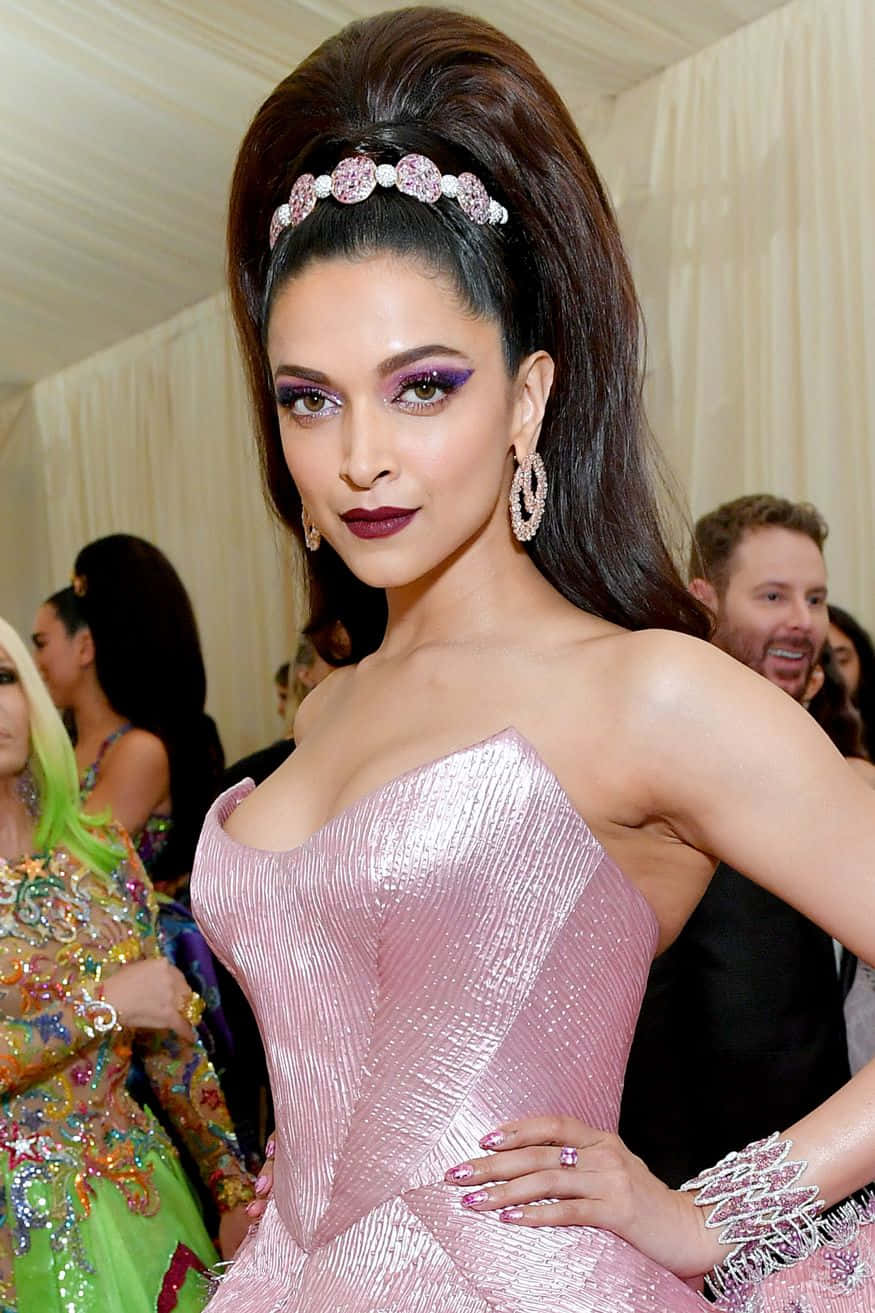 Met Gala 桌布 壁紙 — 一位魅力四射的女性身穿閃亮粉紅禮服，搭配紫色眼妝，在高級時尚活動中自信擺姿勢。