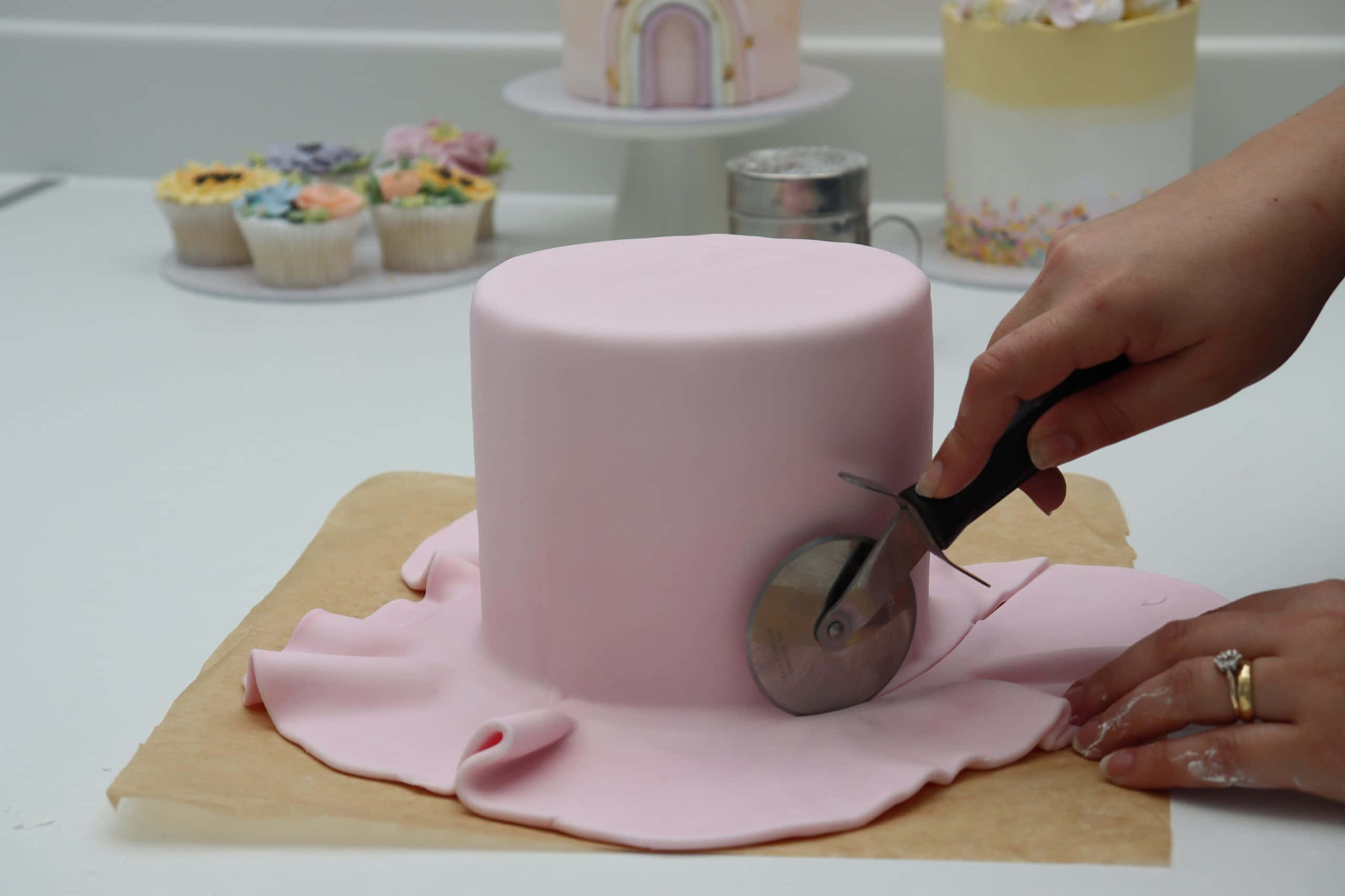 Cake Fondant 桌布 壁紙 — 一位麵包師傅用披薩切刀將牛油紙上圓形蛋糕的平滑粉紅色翻糖切掉。