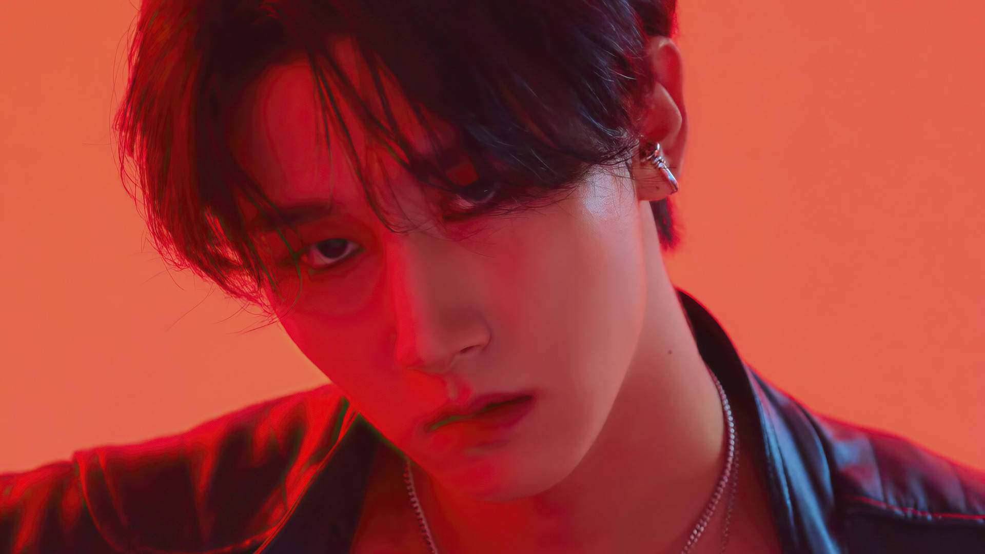 Monsta X IM Fatal Love 壁紙 — 一位黑髮、眼神銳利的年輕男子在戲劇性的紅光下，對著純橙色背景直視前方。