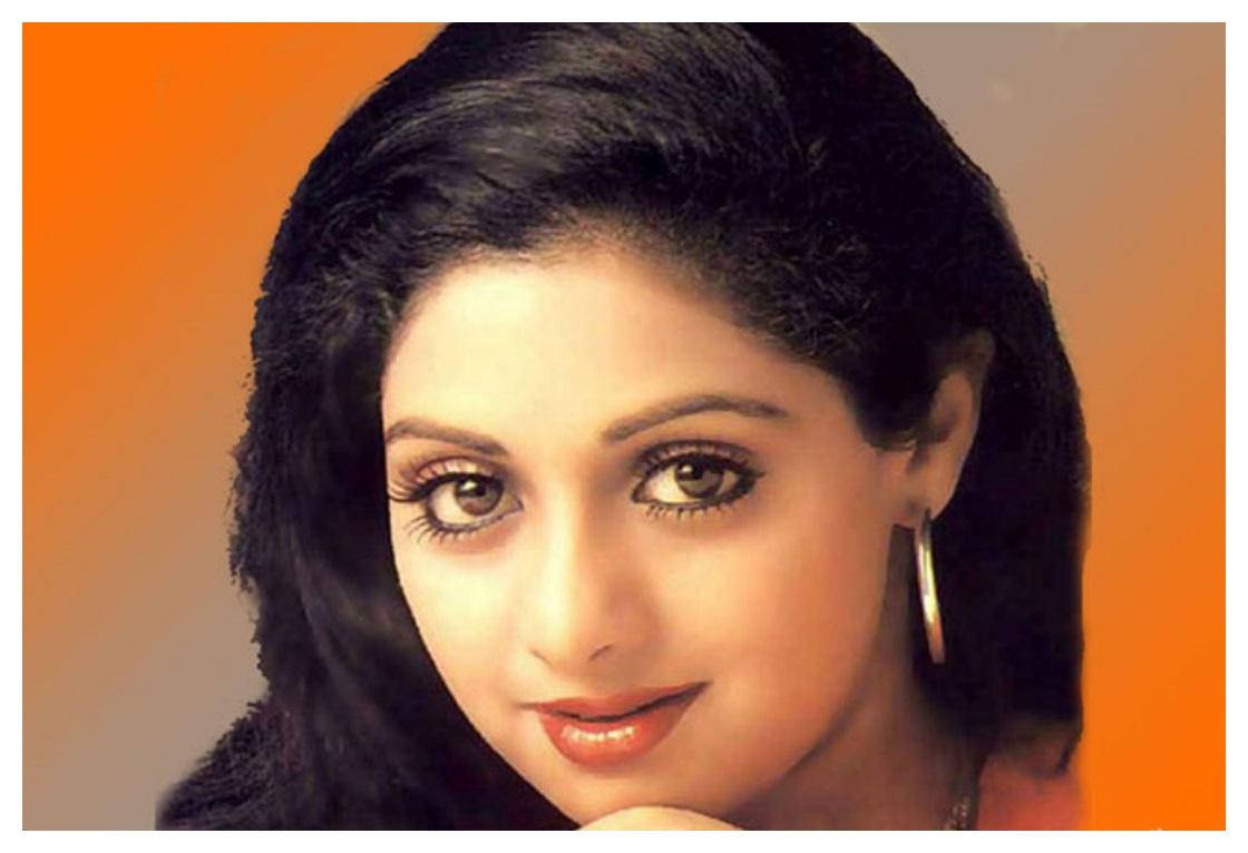 Sridevi 桌布 壁紙 — 一位黑髮、笑容溫暖的女子的特寫肖像，背景為橙色漸變。