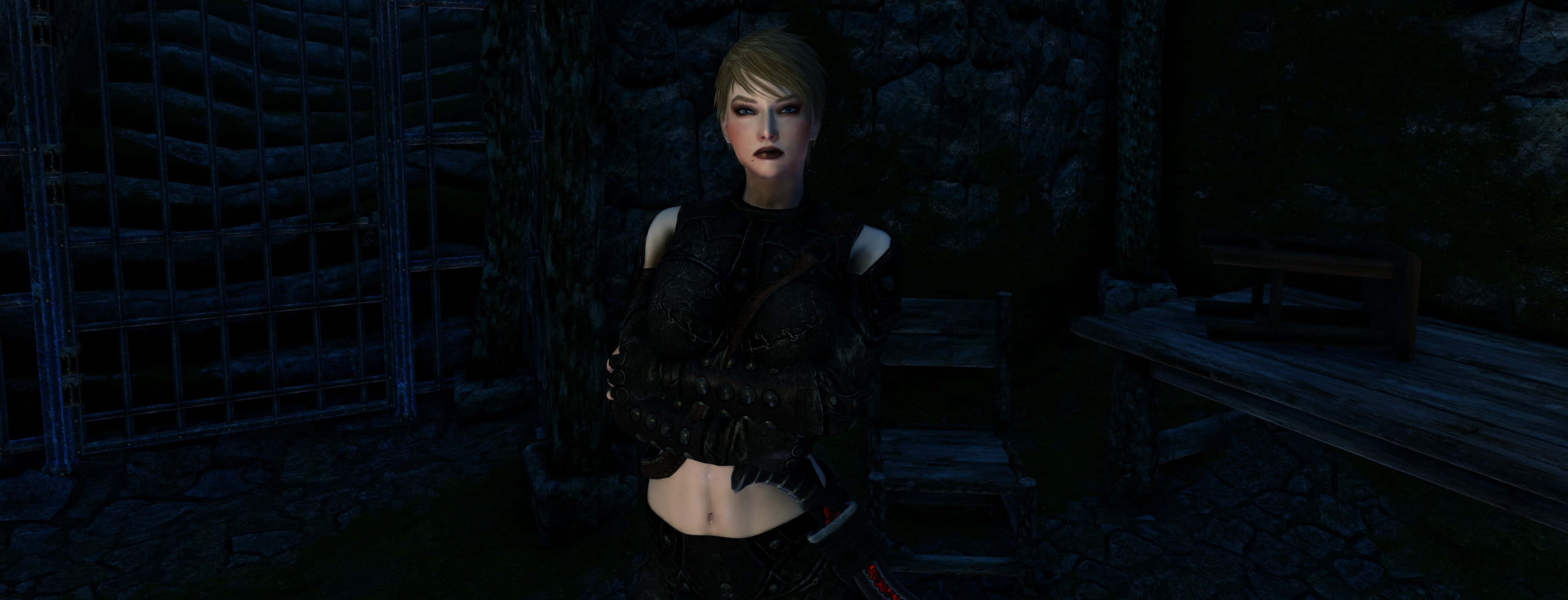 Skyrim Astrid 桌布 壁紙 — 一位黑髮女子身穿黑色盔甲，站在一個有鐵欄窗戶和木凳的昏暗石頭地牢中。