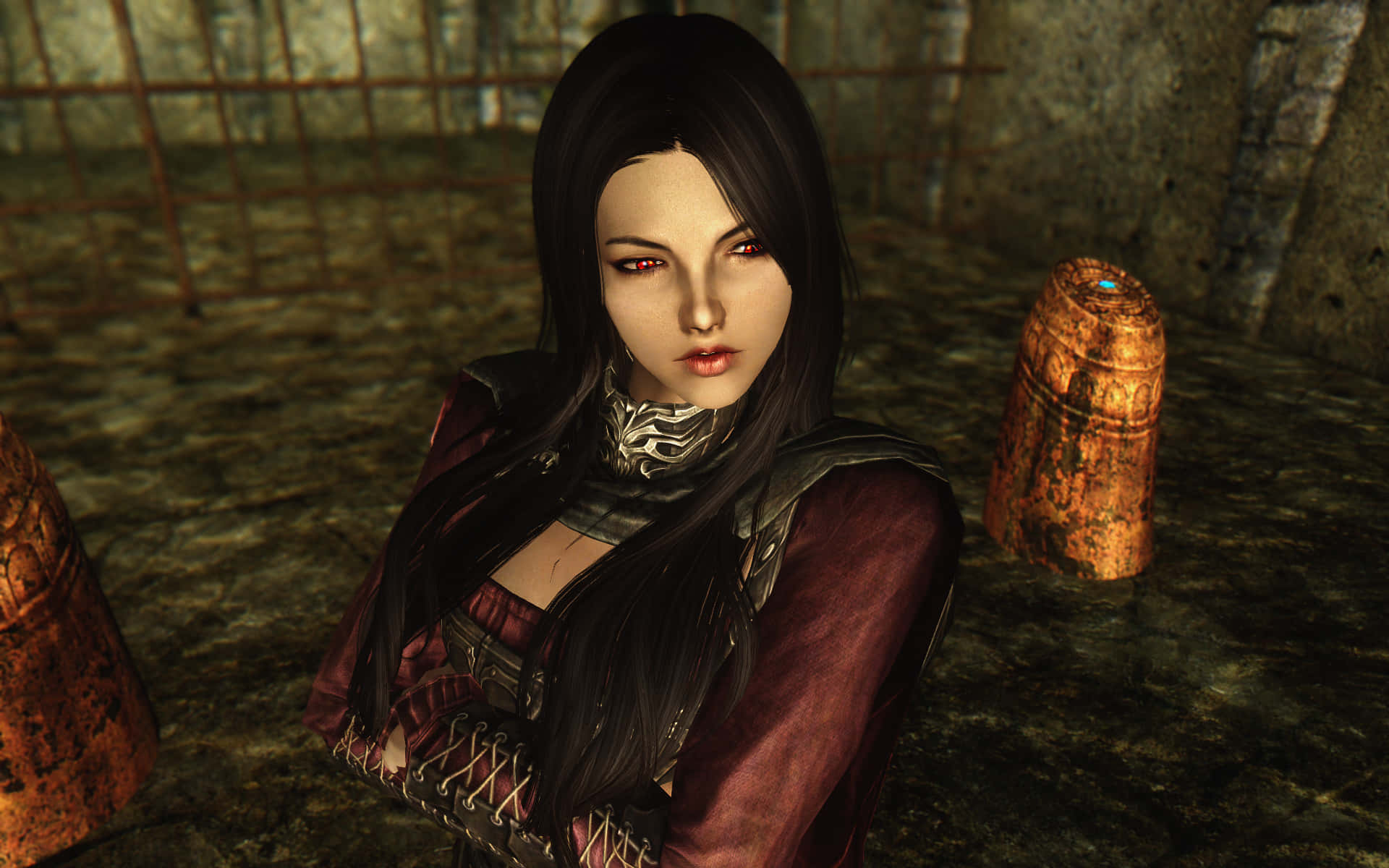 Skyrim Serana 桌布 壁紙 — 一位黑髮女戰士，擁有紅色眼睛和華麗盔甲，站在一個昏暗的地牢中，周圍有生鏽的木桶和石牆。