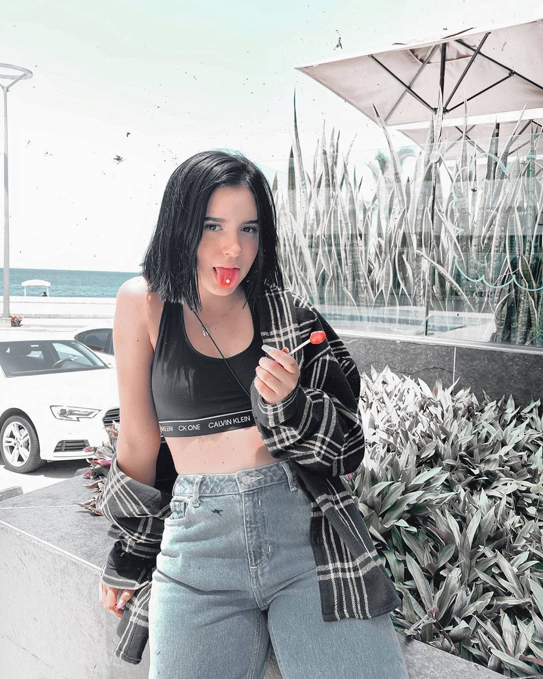 年輕女性在海邊伸出舌頭手持紅色棒棒糖。 — TikTok GIF 壁紙