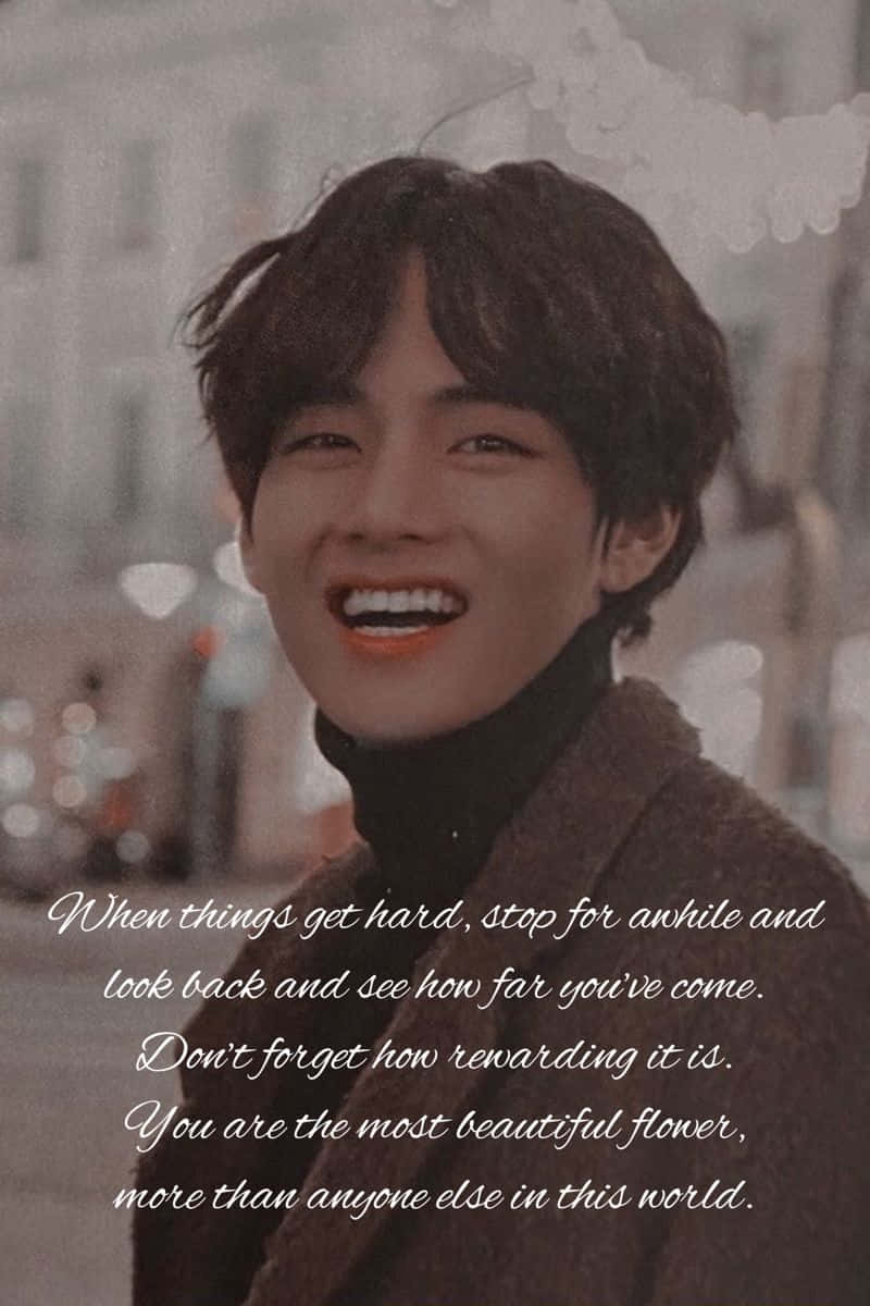 Bts Inspirational 桌布 壁紙 — 一位黑髮的快樂年輕男子在柔和模糊的城市背景中，伴隨著溫暖的散景燈光，開懷大笑。