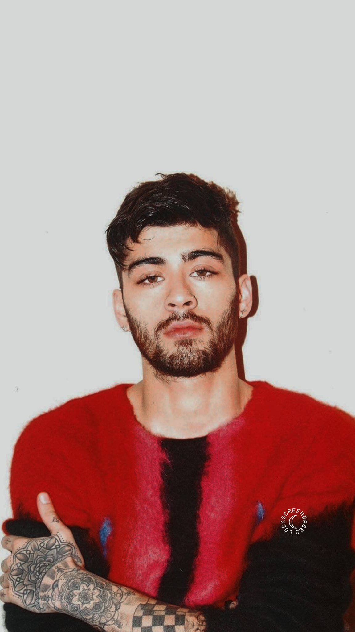 One Direction 桌布 壁紙 — 一位黑髮鬍鬚的年輕男子穿著紅黑絨毛毛衣，直視鏡頭，手臂上的紋身清晰可見。