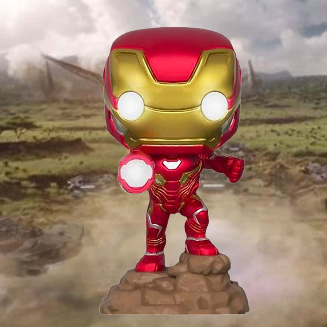Iron Man Pop Figures 桌布 壁紙 — 一個 Funko Pop 鐵甲奇俠人偶站在岩石底座上，背景是煙霧瀰漫的戰場。
