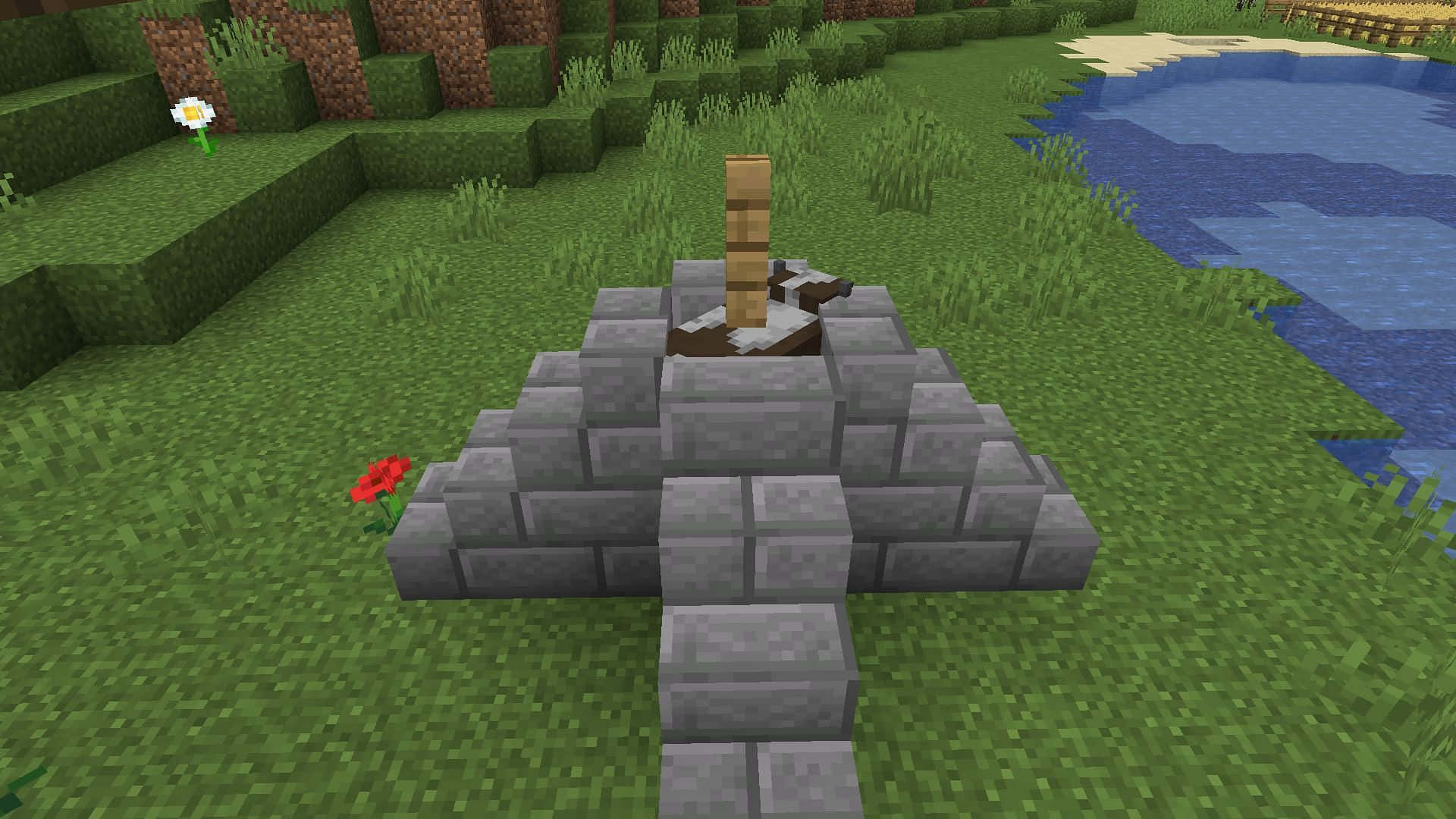 Minecraft Cow 桌布 壁紙 — 一個Minecraft石頭紀念碑，帶有木柱和斷劍，矗立在藍色水域旁邊的草地上。