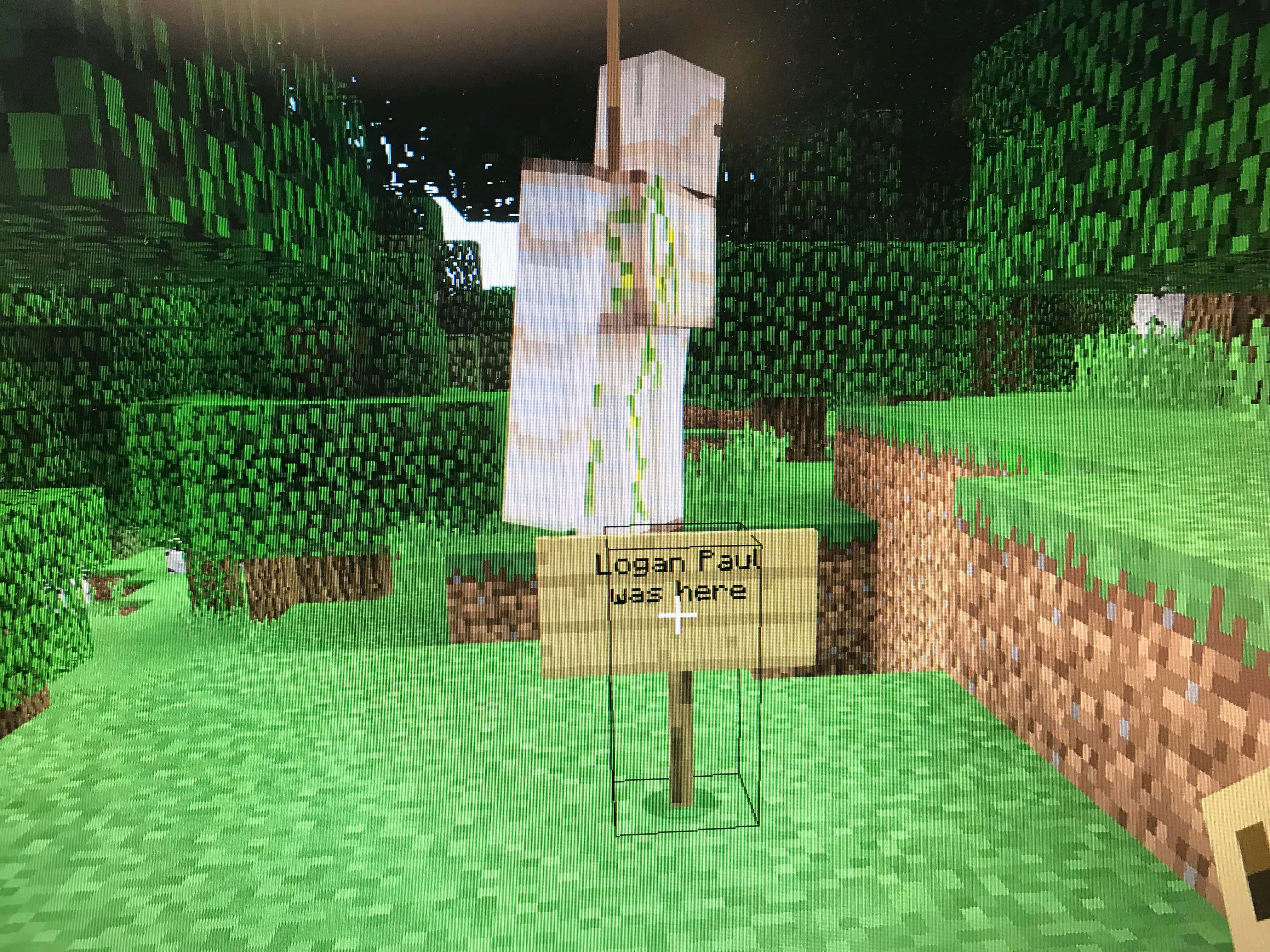 Minecraft Education Edition 桌布 壁紙 — 一個Minecraft角色喺夜晚嘅像素化森林入面企喺一個寫住Logan Paul was here嘅標誌旁邊。