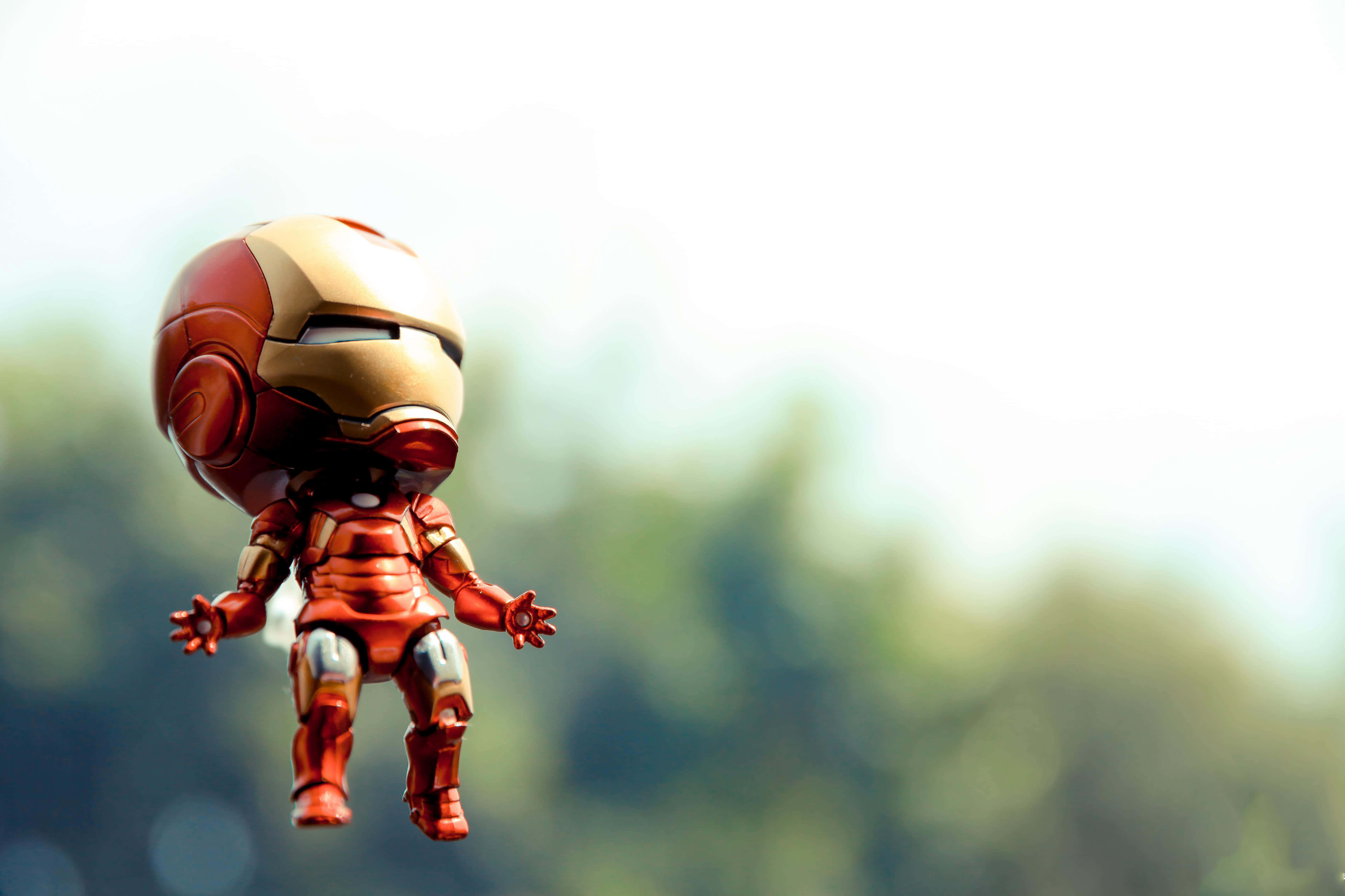 Iron Man Bobbleheads 桌布 壁紙 — 一個Q版鐵甲奇俠人偶喺柔和模糊嘅綠色同白色背景前凌空漂浮。