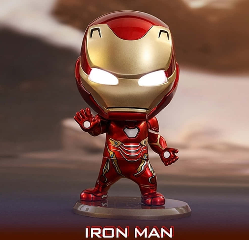 Iron Man Bobbleheads 桌布 壁紙 — 一個Q版風格的鐵甲奇俠可動人偶，帶有發光的眼睛和斥力手，站在底座上，背景是模糊的沙漠。