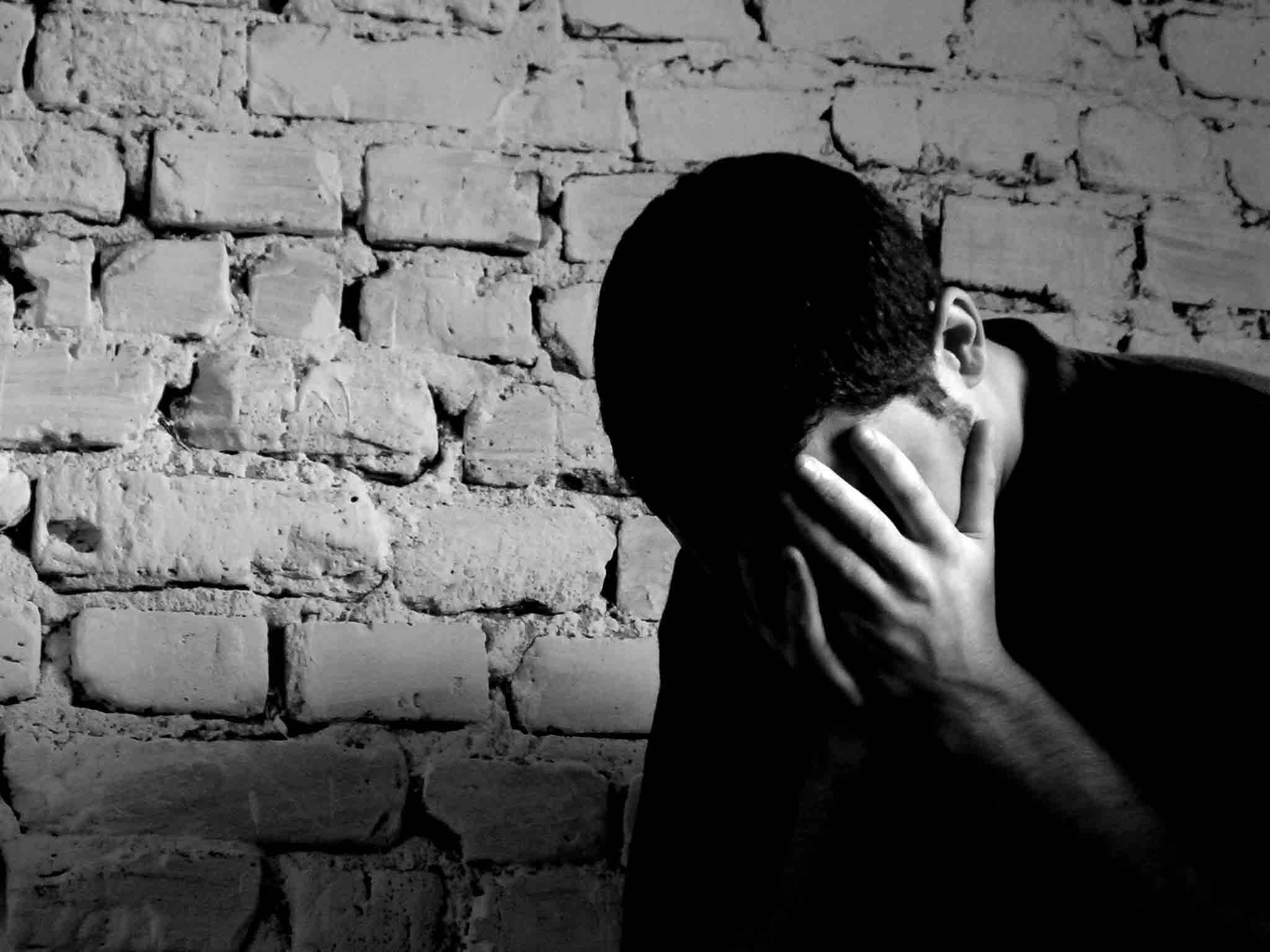 emo 桌布 壁紙 — 一個人以剪影形式，雙手掩面，靠著紋理磚牆，呈單色調。