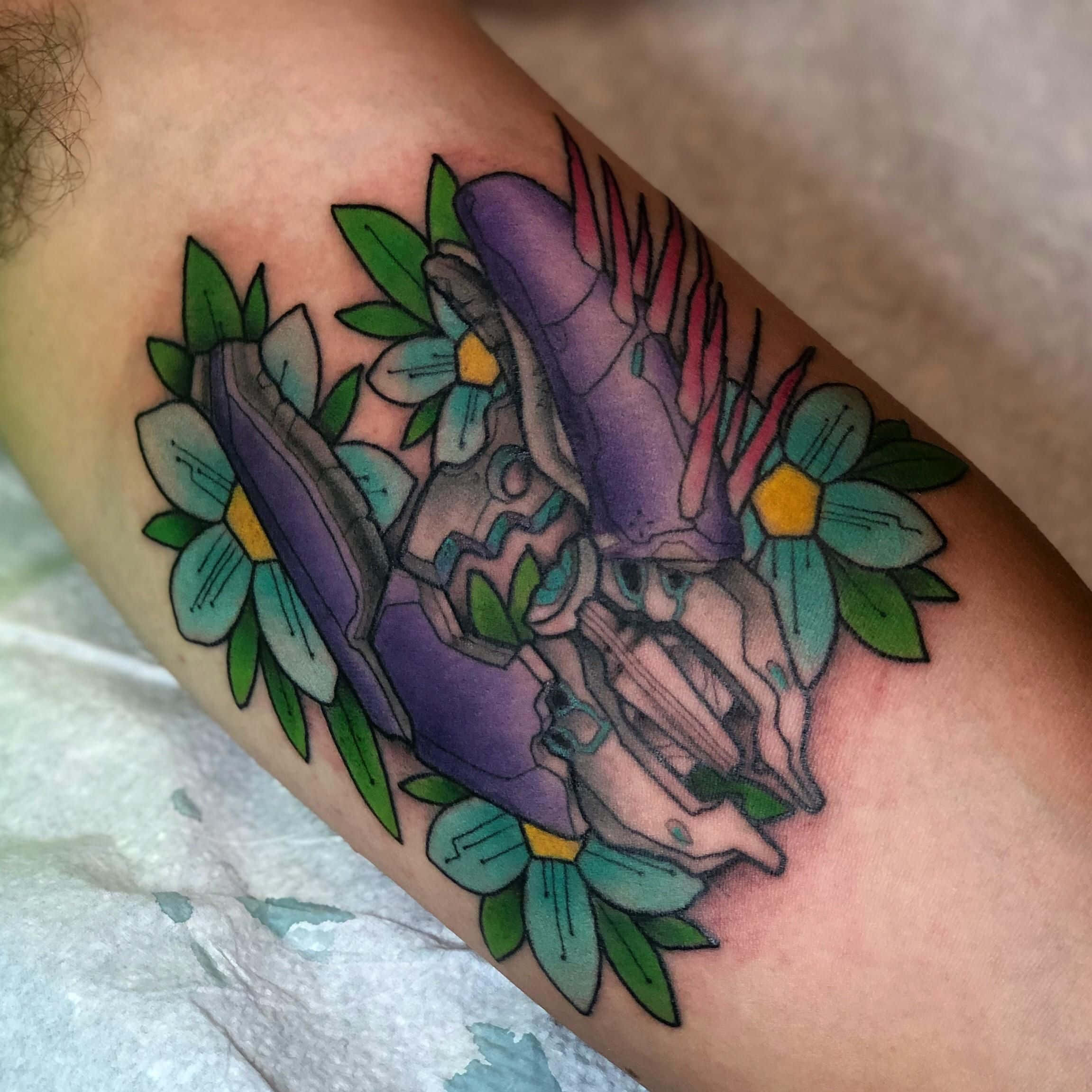 Halo Needler 桌布 壁紙 — 一個人前臂上嘅紫色機械臂紋身，周圍環繞著青綠色花朵同綠色葉子，色彩鮮豔。