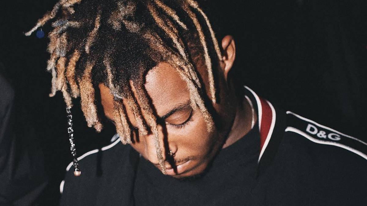 Juice WRLD 桌布 壁紙 — 一個人嘅特寫肖像，長辮子頭髮，喺黑色背景下着住黑色D&G外套。