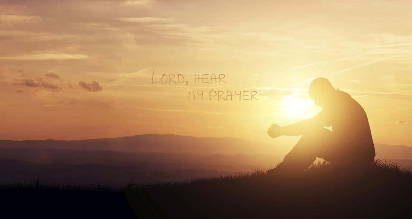 Praying 桌布 壁紙 — 一個人在日落時分跪在山頂祈禱的剪影，溫暖的橙色天空上疊加文字 'LORD HEAR MY PRAYER'。