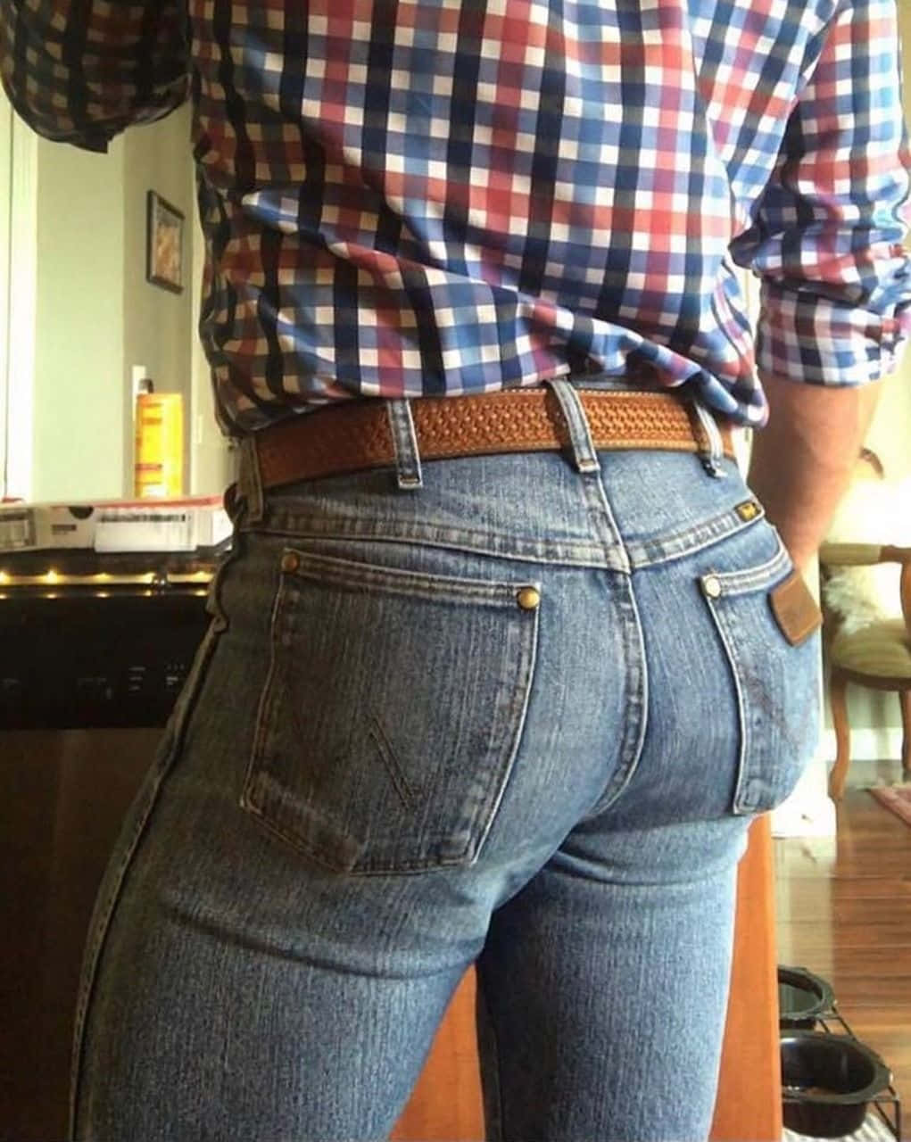 Jeans 桌布 壁紙 — 一個人在溫暖燈光的室內環境中，穿著藍色牛仔褲和格子襯衫，搭配棕色皮帶的背部特寫。