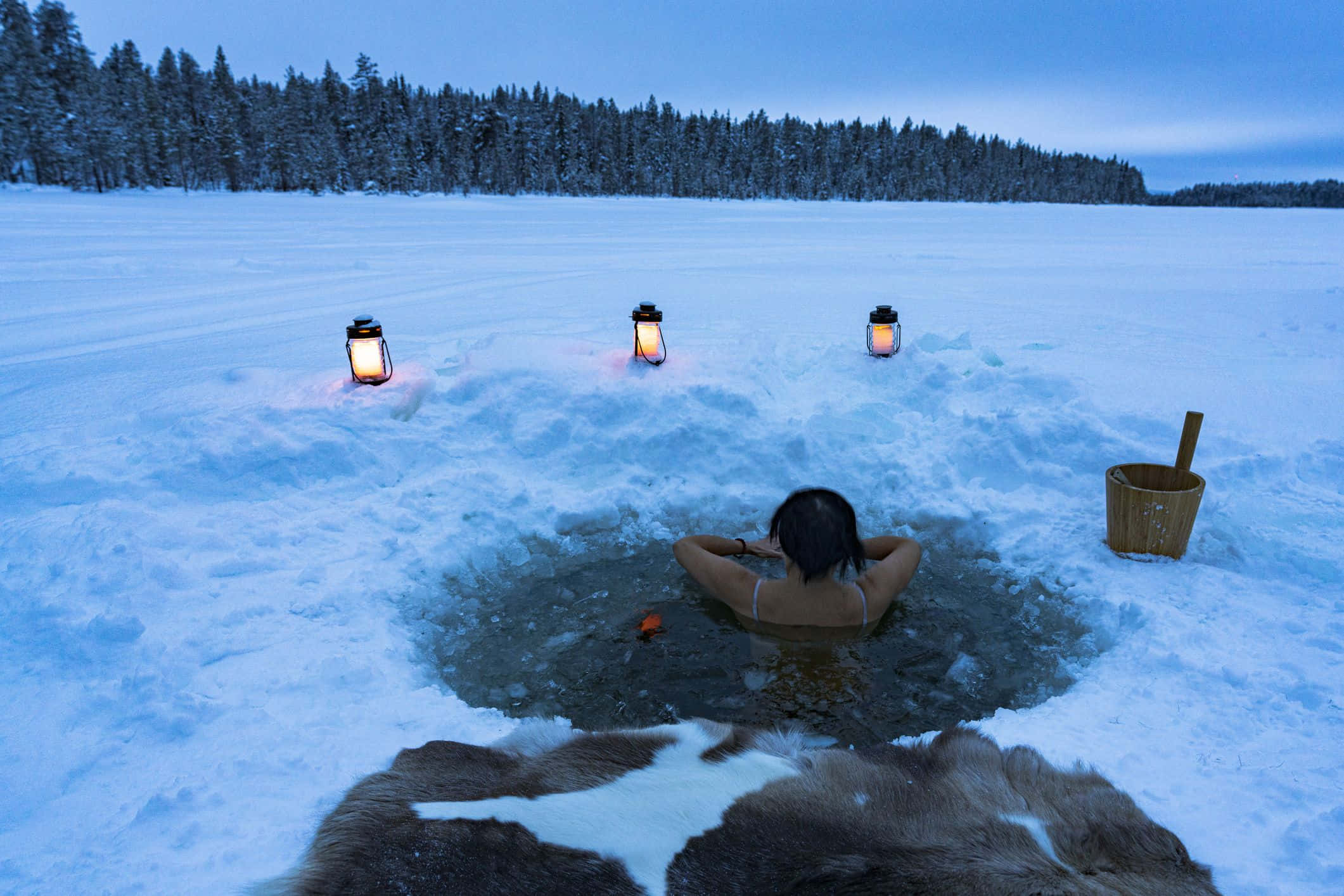 寒冷 桌布 壁紙 — 一個人在被發光燈籠和暮色森林環繞的雪地冰洞浴中放鬆。