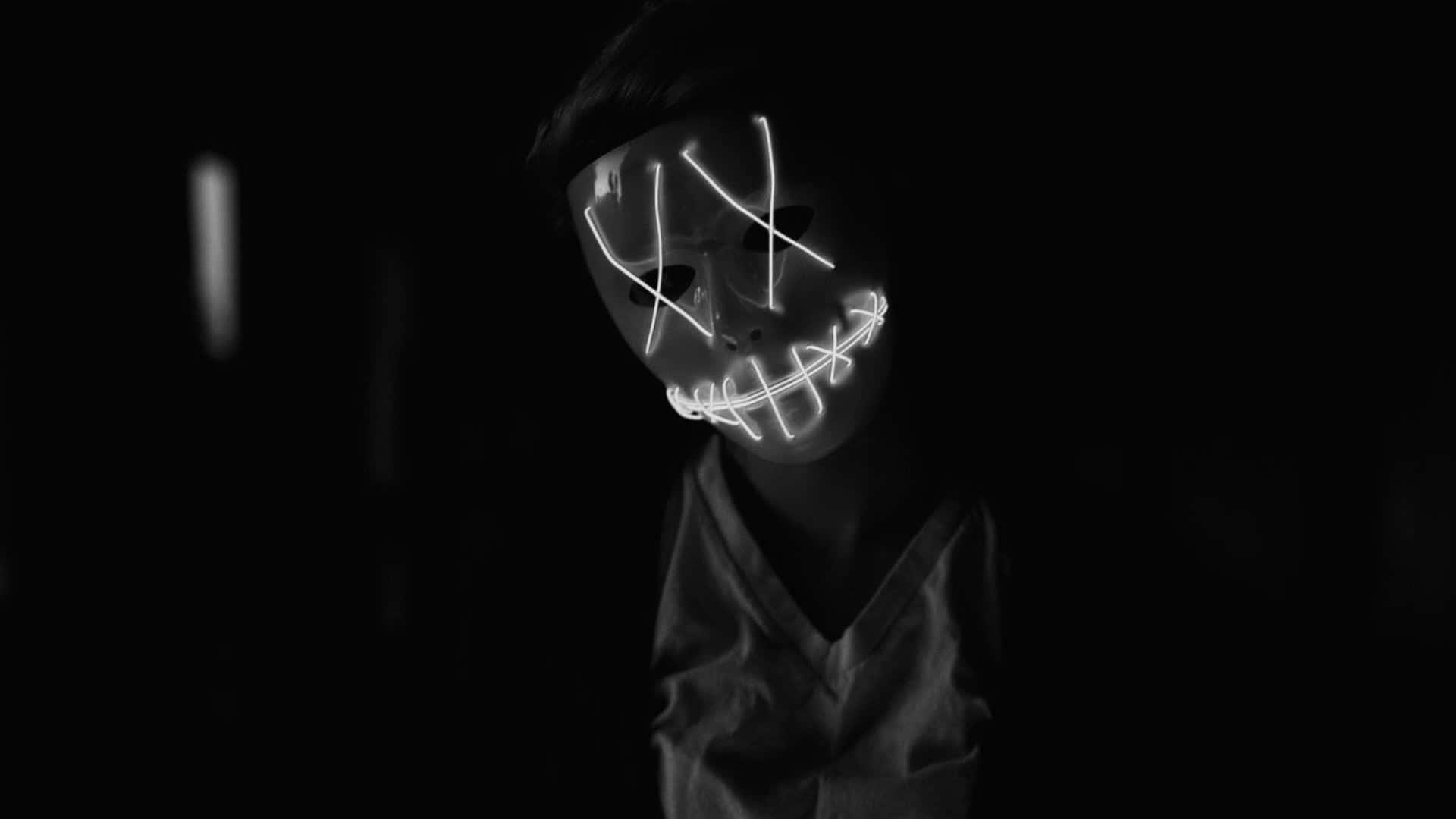 Halloween Masks 桌布 壁紙 — 一個人戴著發光的白色LED面具，嘴巴縫合，眼睛交叉，從完全的黑暗中凝視。