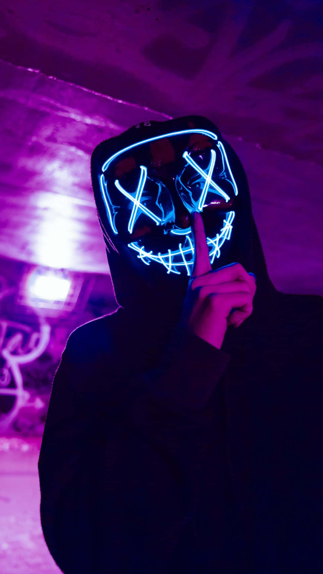 Horror Masks 桌布 壁紙 — 一個人戴著發光藍色LED面具，眼睛呈X形，嘴巴被縫合，在紫色霓虹燈下將手指放在嘴唇上。