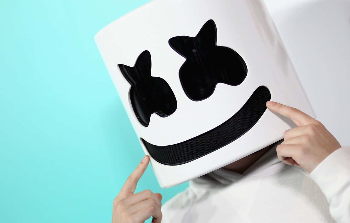 Marshmello 桌布 壁紙 — 一個人戴著白色Marshmello頭盔，上面有黑色笑臉，在藍綠色背景上指向它。