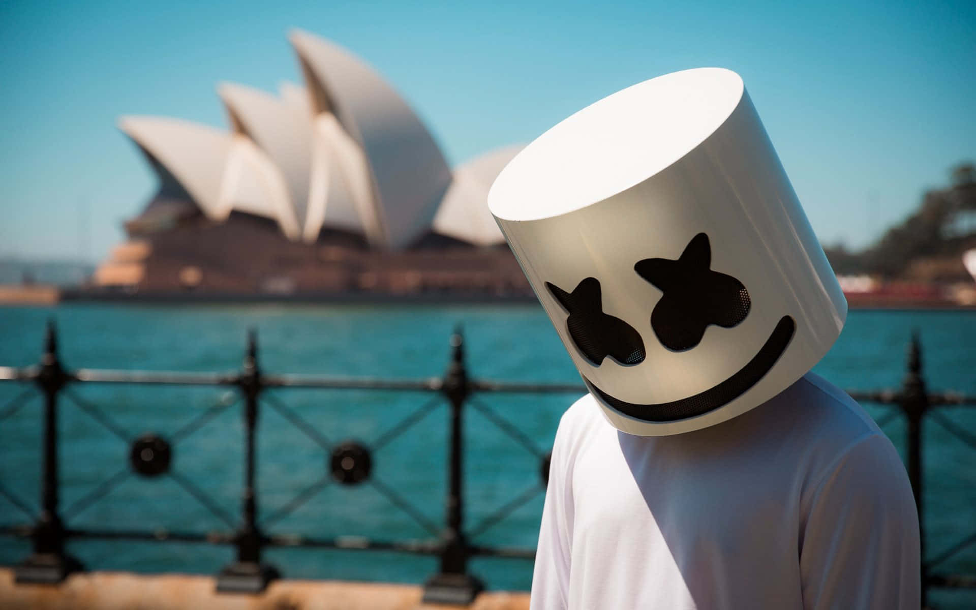 Marshmello 桌布 壁紙 — 一個人戴著白色棉花糖頭盔，站在晴朗藍天下標誌性的悉尼歌劇院前。