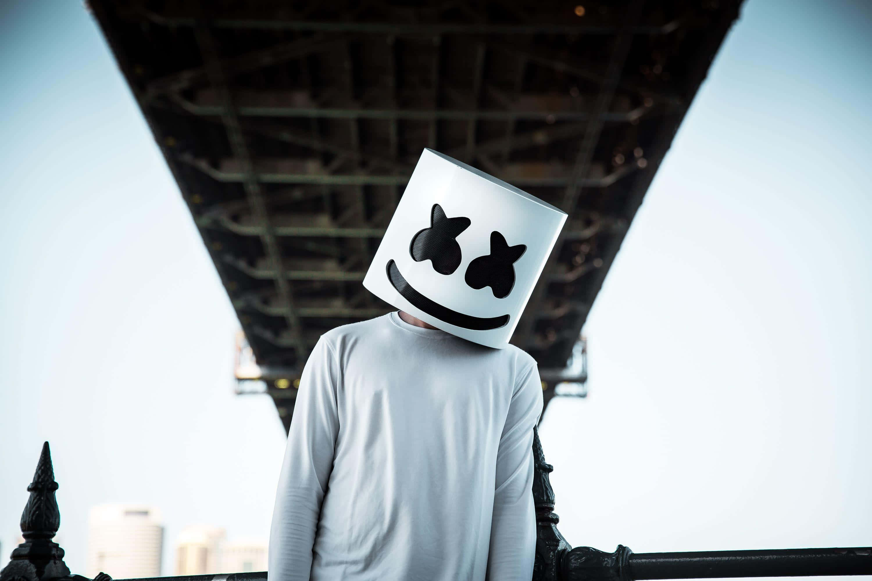 Marshmello 桌布 壁紙 — 一個人戴著白色棉花糖頭盔站在橋下，背景是城市天際線。