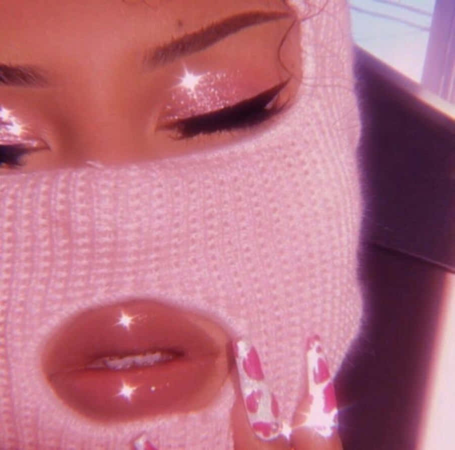 Baddie Vintage 90's Aesthetic 桌布 壁紙 — 一個人戴著粉紅色針織面罩的特寫，眼睛和嘴唇閃閃發光，手上有粉紅色豹紋指甲觸摸面罩。