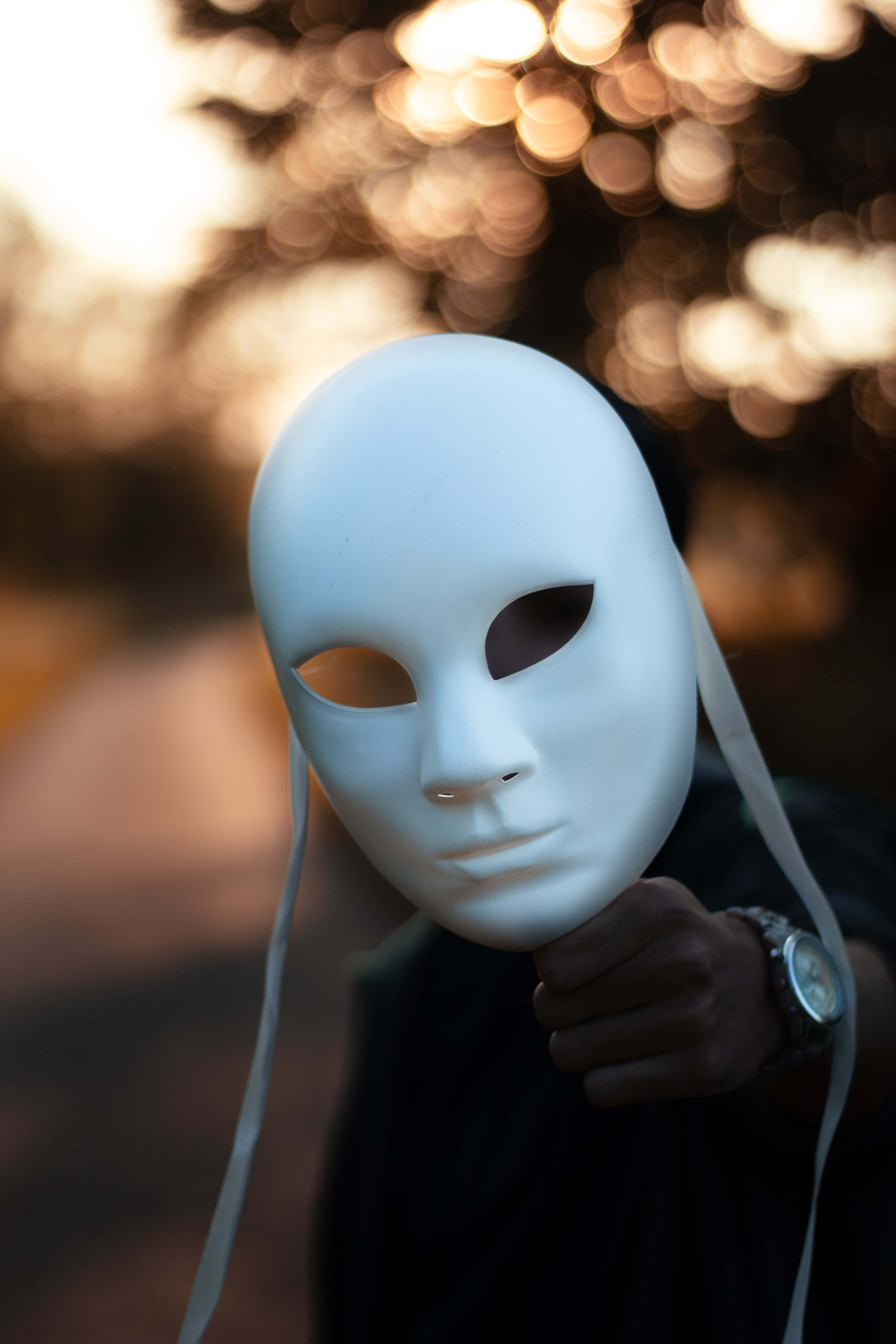 Mask 桌布 壁紙 — 一個人手持白色戲劇面具，背景是溫暖的散景效果，金色陽光穿過樹林灑落。