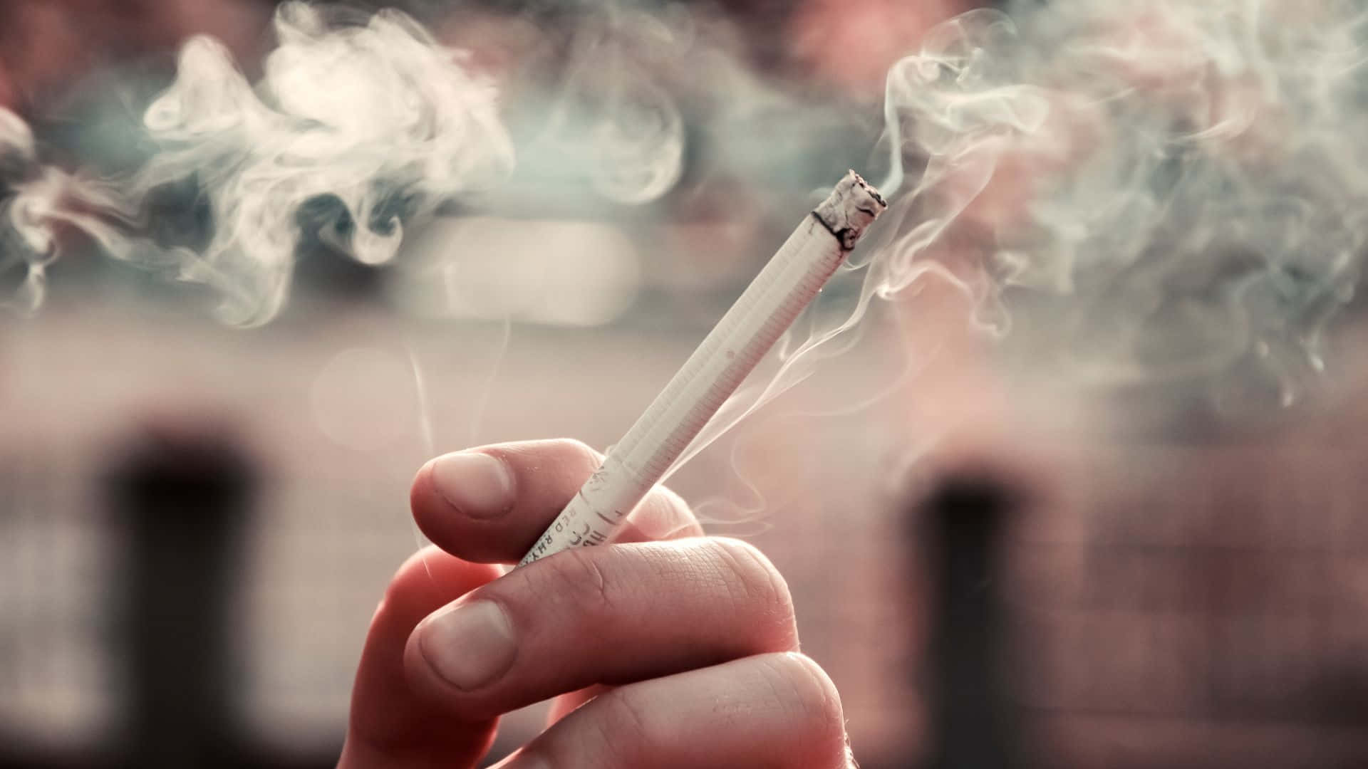 一個人手持香煙，煙霧裊裊升起 壁紙