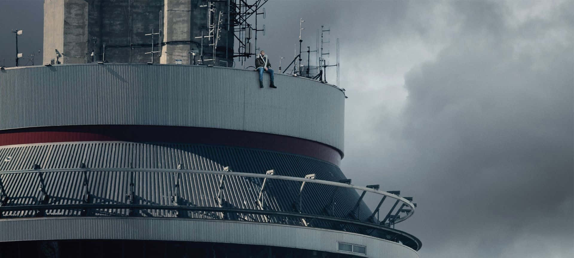 Drake 桌布 壁紙 — 一個人獨自坐在一座風化的工業塔頂，天空陰沉密佈。
