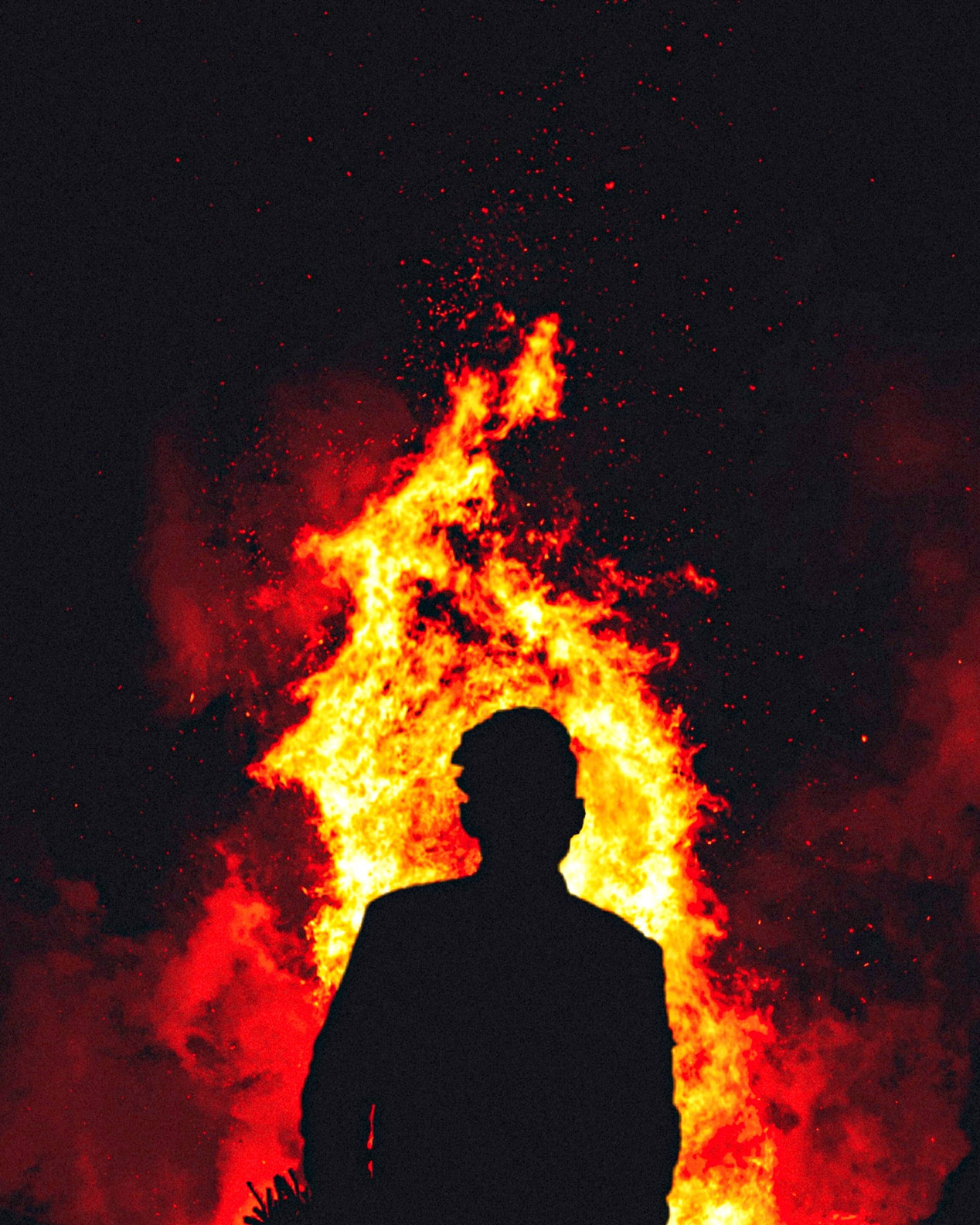 男人 桌布 壁紙 — 一個人的剪影站在熊熊烈火前，火花在黑暗的夜空中飛舞。