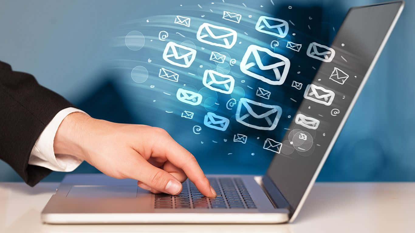 Email 桌布 壁紙 — 一個人的手在筆記型電腦上打字，發光的電子郵件圖示像數位爆發一樣在螢幕周圍旋轉。