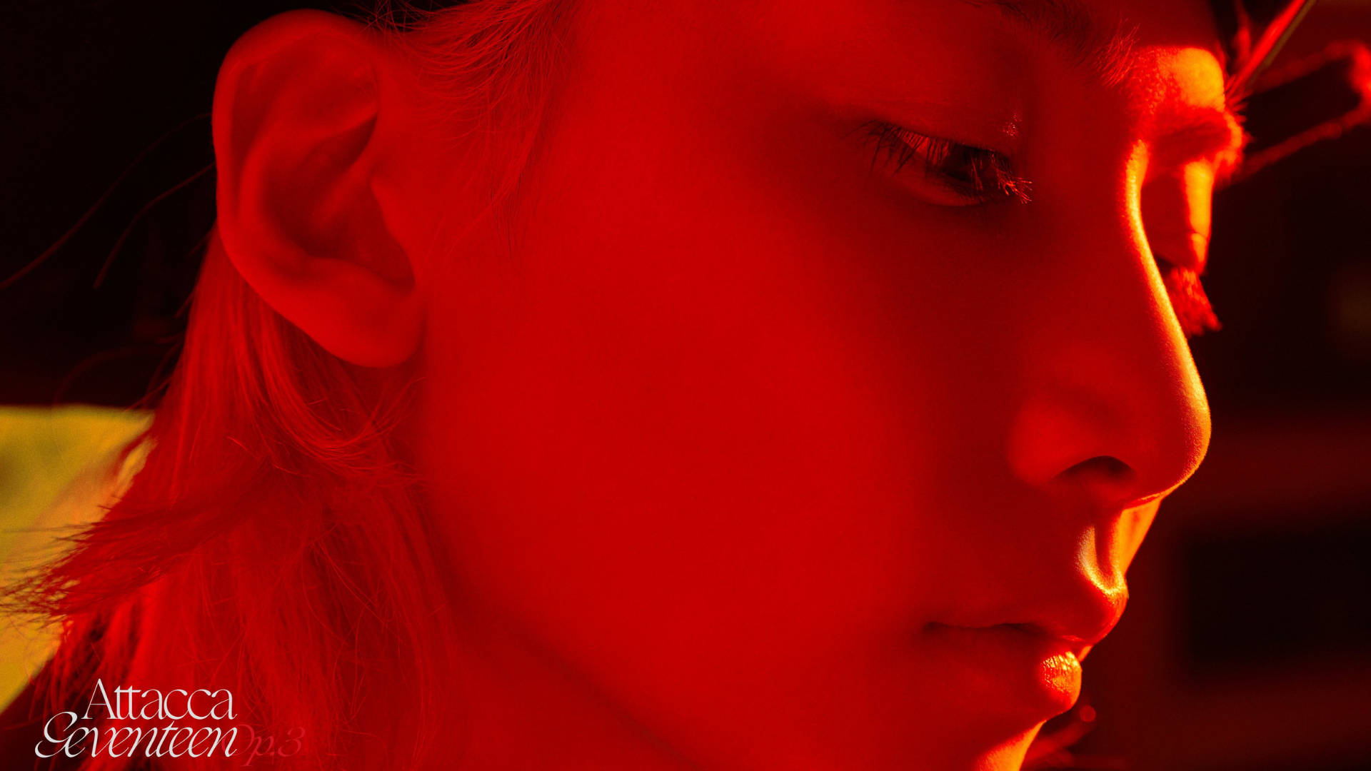 Yoon Jeonghan Attacca 壁紙 — 一個人的臉龐沐浴在強烈的紅光中，柔和的陰影突顯了他們的側面和閉上的眼睛。