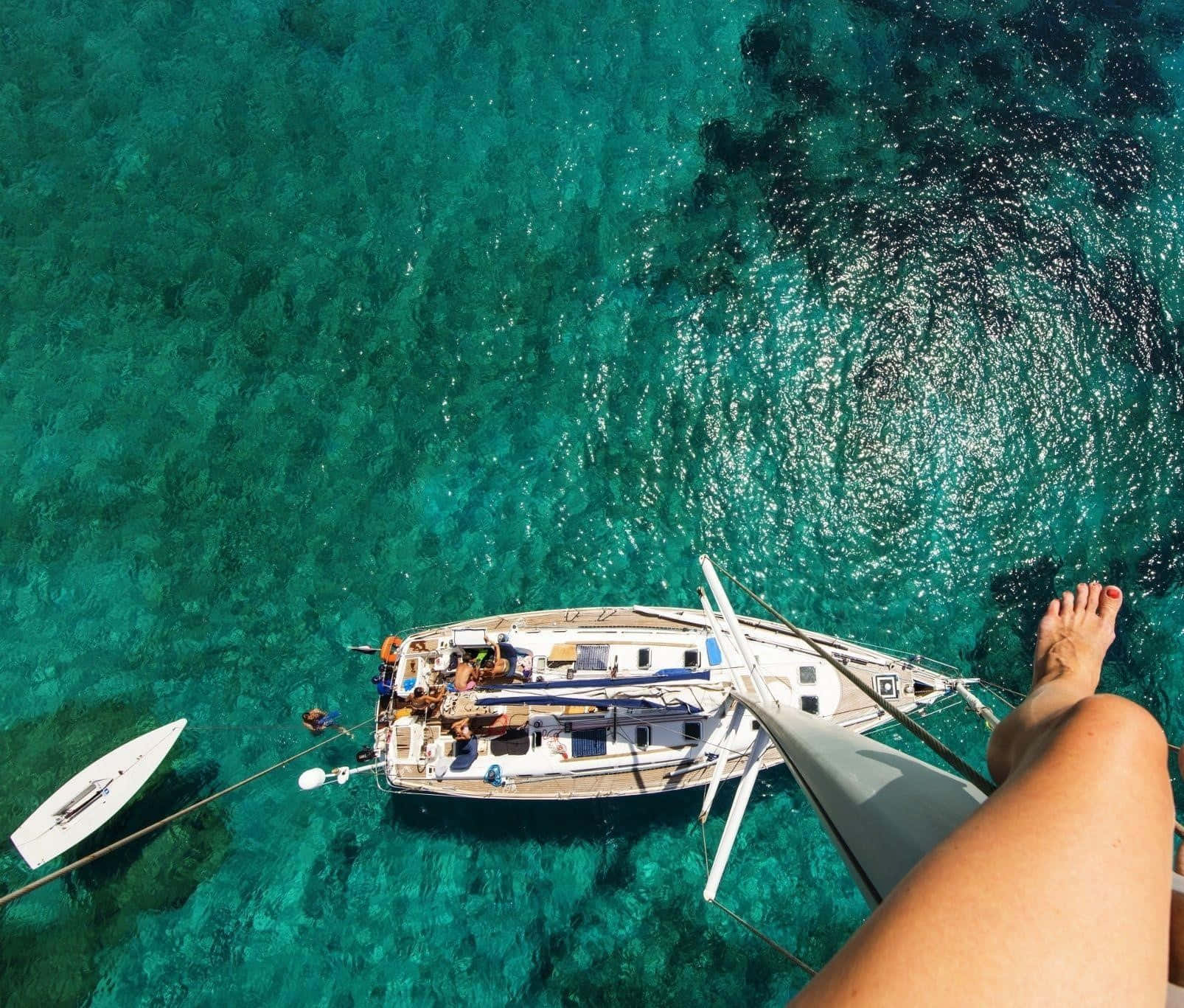 Yacht 桌布 壁紙 — 一個人的赤腳懸掛在停泊於清澈碧綠海水中的帆船上方。