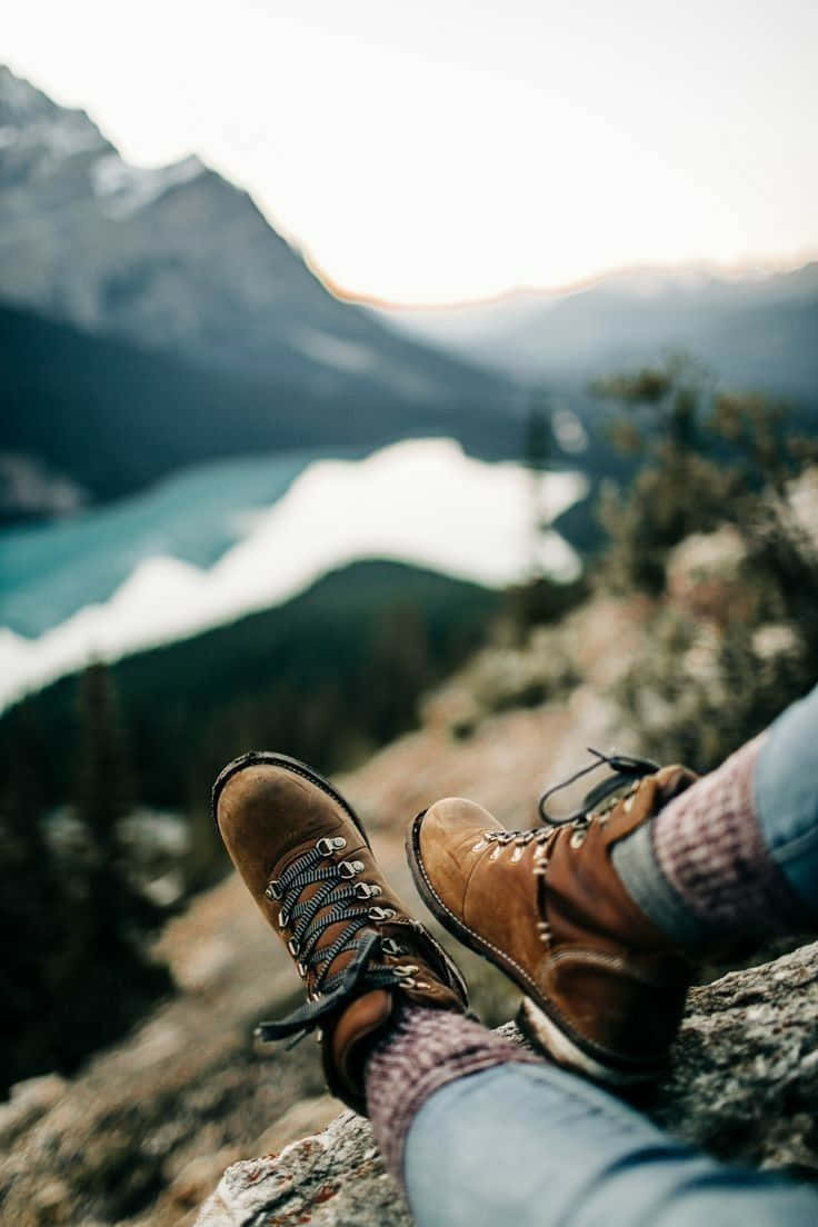 Winter Hiking 桌布 壁紙 — 一個人的遠足靴放在岩石突出處，俯瞰日落時寧靜的山中湖泊。