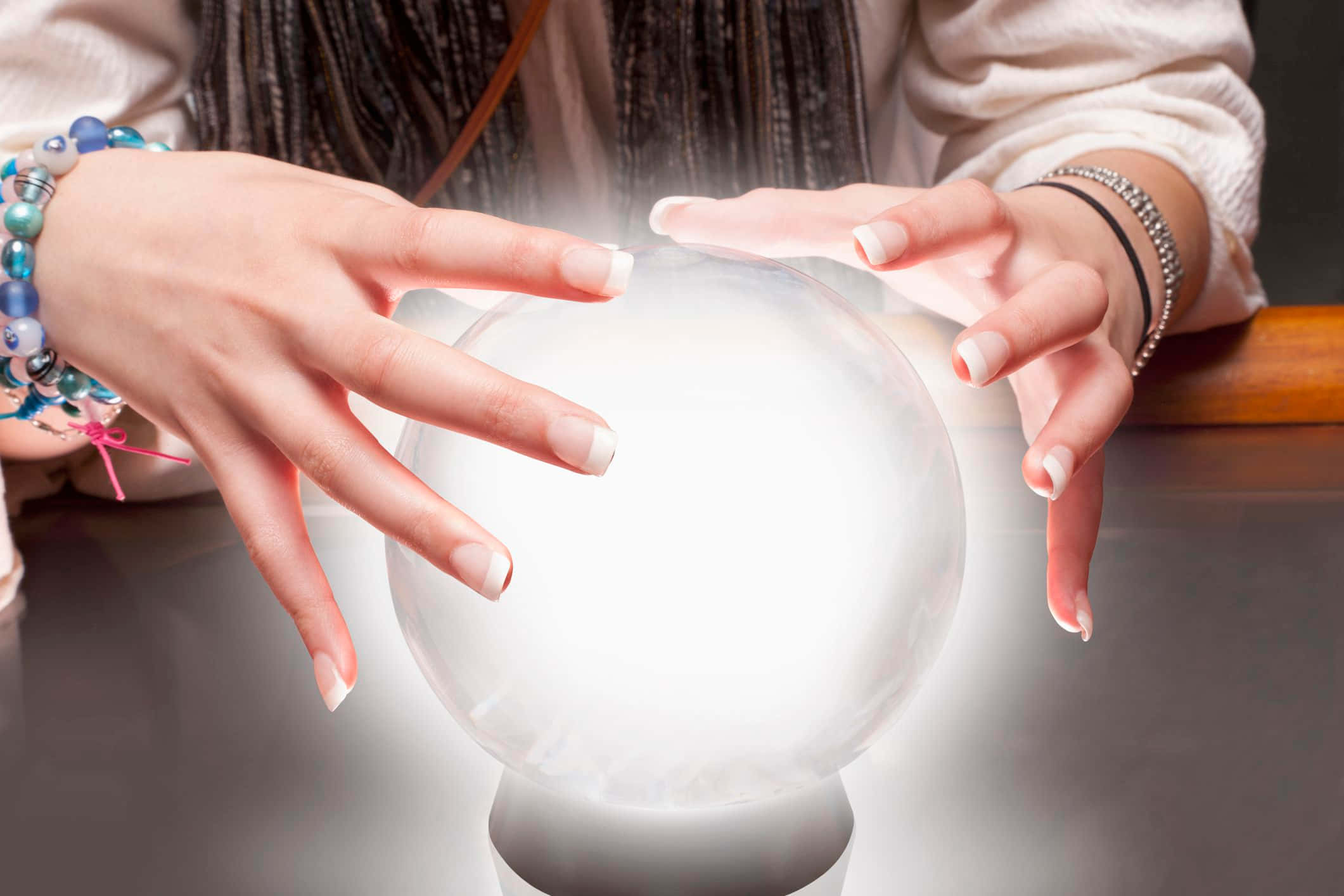 Crystal Ball 桌布 壁紙 — 一個人的雙手懸浮在一個發光的 crystal ball 上方，散發出柔和的霧氣，置於暗色桌上。