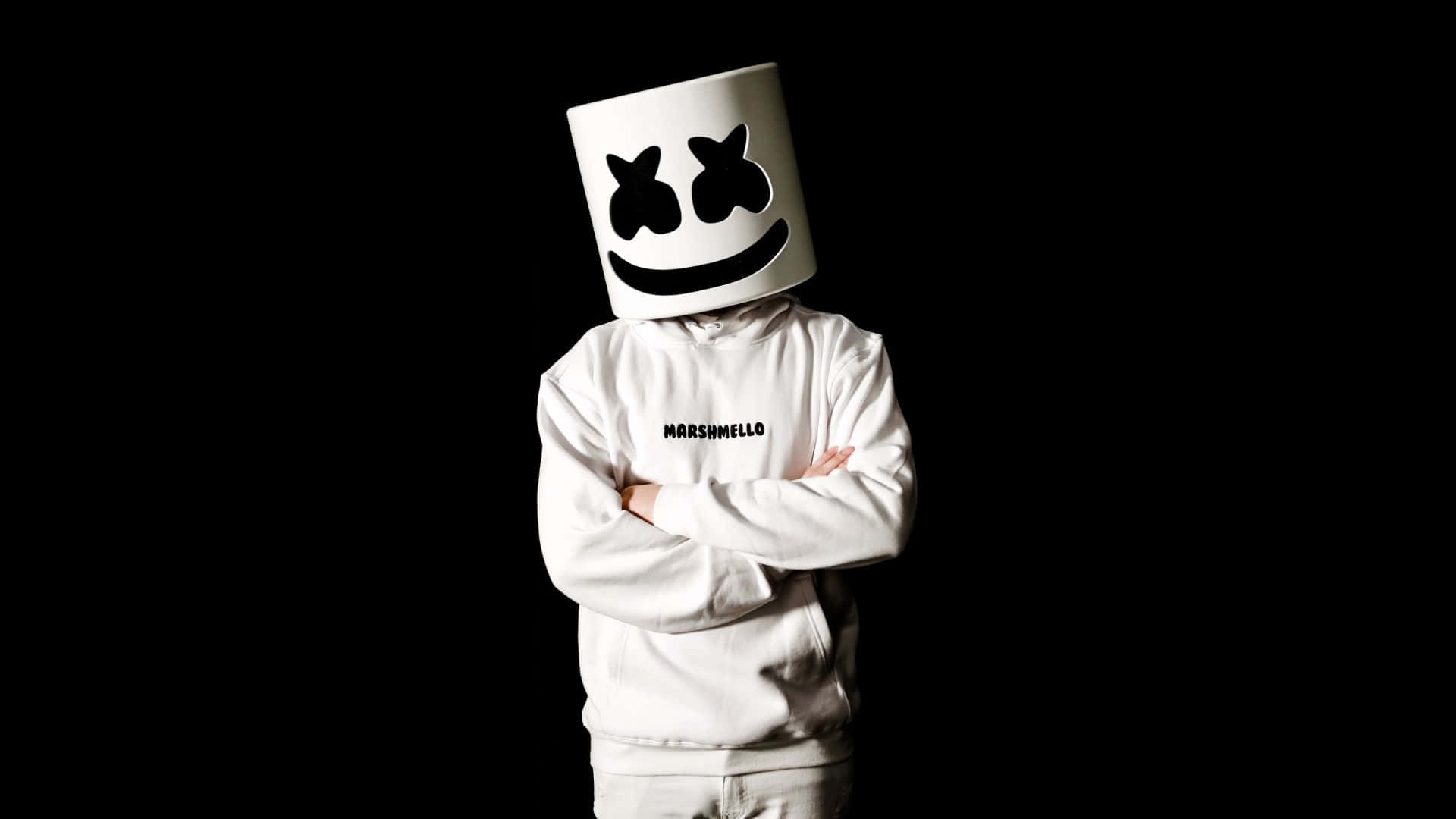 Marshmello 桌布 壁紙 — 一個人穿著白色連帽衫和標誌性的棉花糖頭盔，雙臂交叉，站在純黑色背景前。