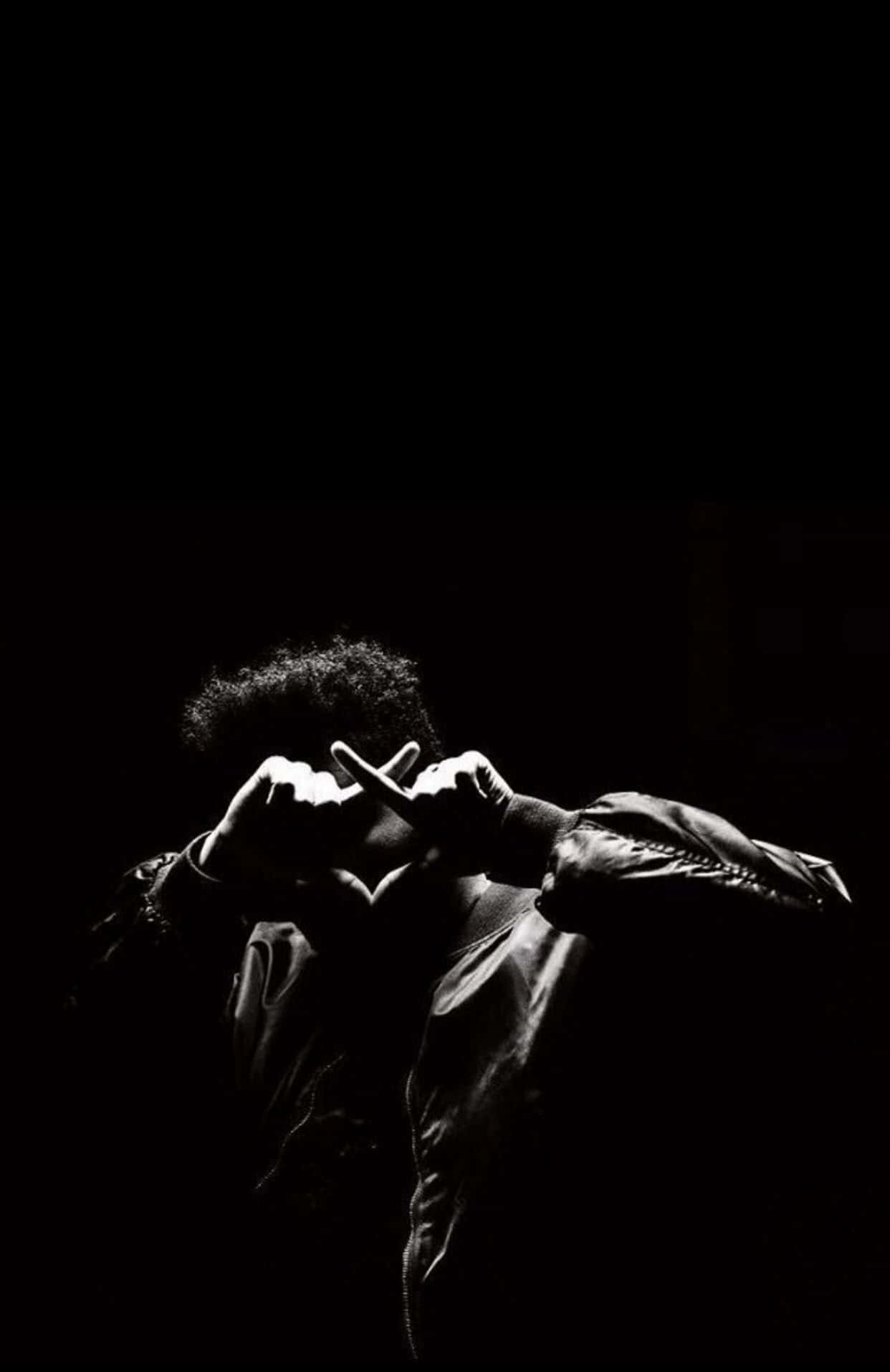 The Weeknd 桌布 壁紙 — 一個人穿著皮褸，在純黑背景前用手做出心形，高對比黑白影像。