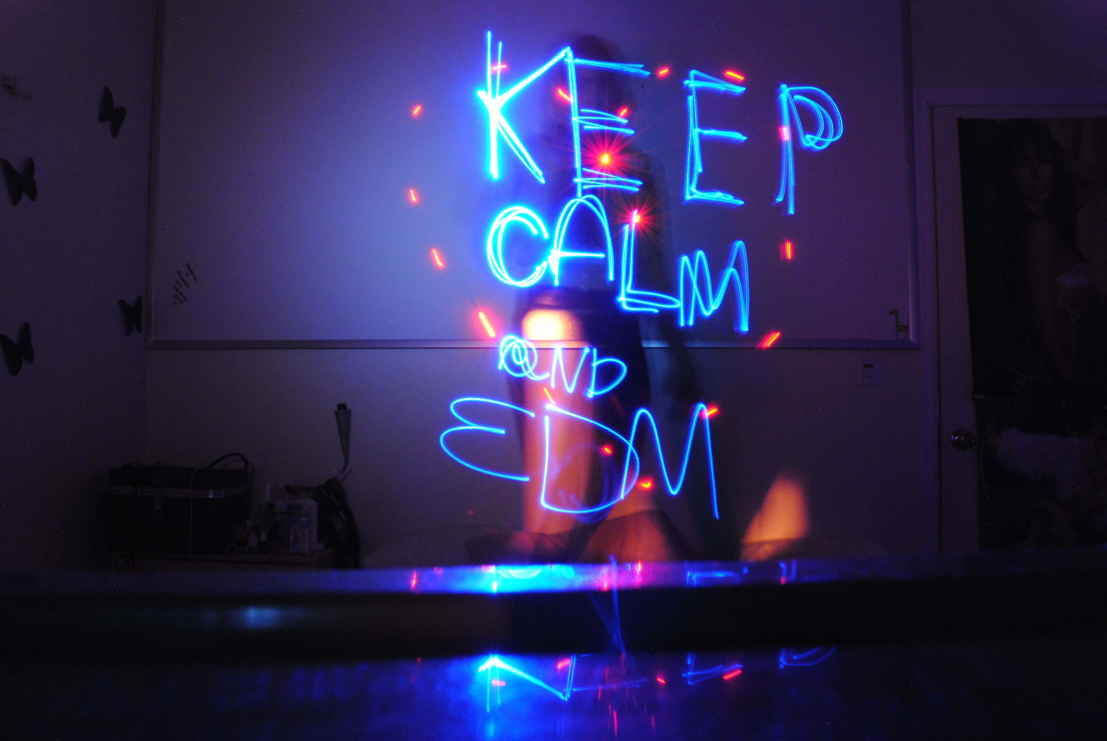 Electronic Dance Music 桌布 壁紙 — 一個人站在發光的藍色霓虹燈後面，燈光拼出 KEEP CALM AND EDM，房間昏暗，牆上有蝴蝶貼紙。