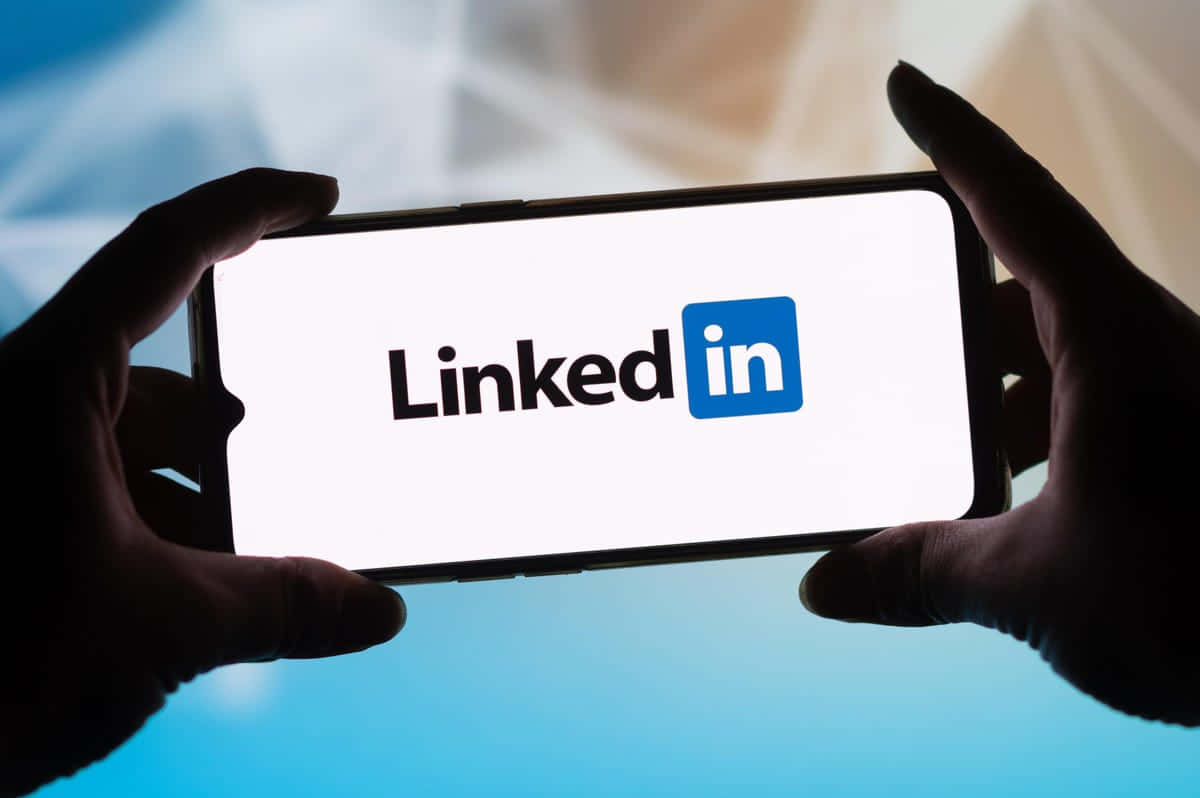 一個人舉起手機，屏幕上顯示LinkedIn標誌 壁紙