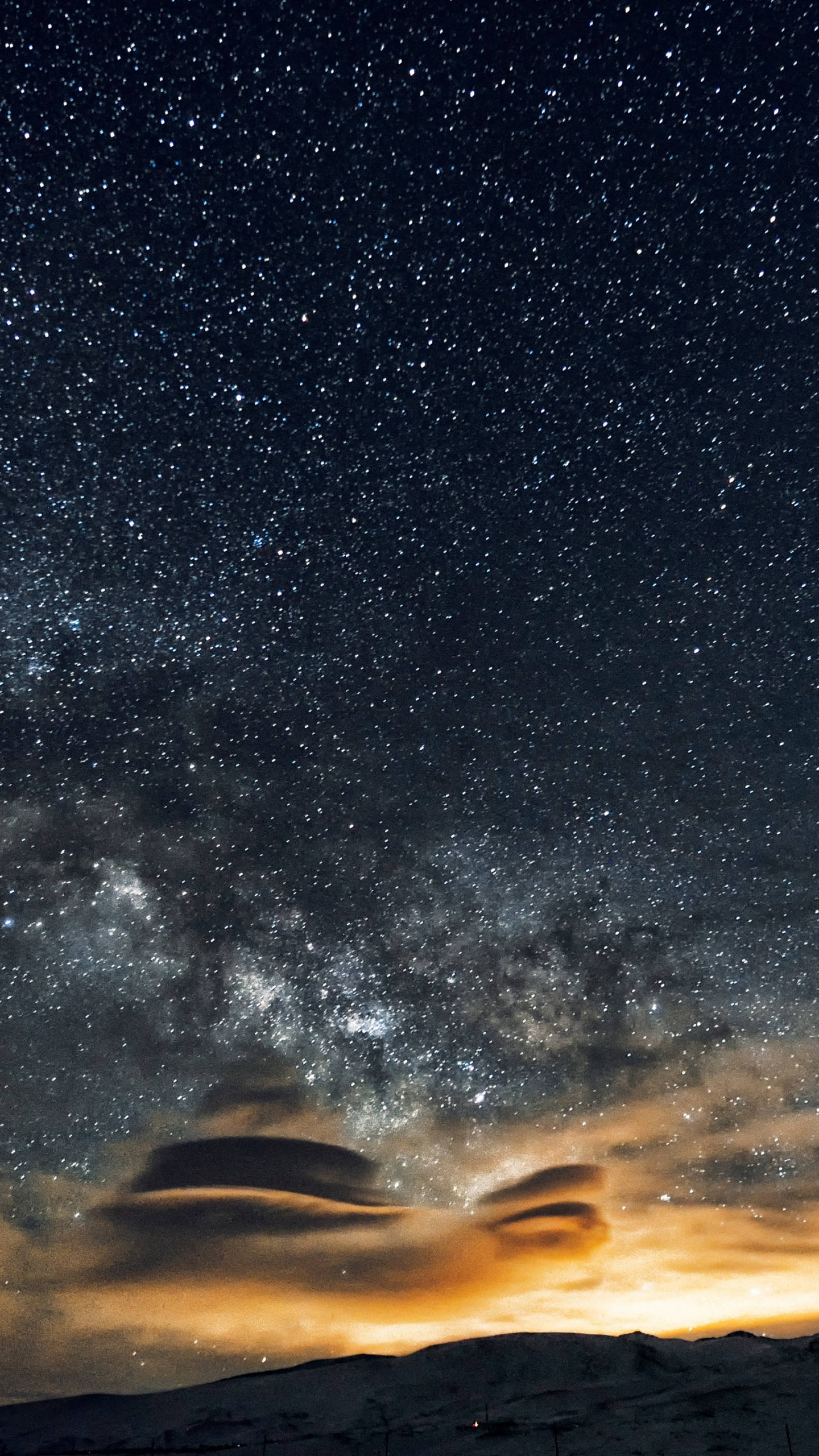 夜空 桌布 壁紙 — 一個令人嘆為觀止的夜空，充滿無數星星和銀河，在發光的雲層下拱形跨越積雪的山峰。