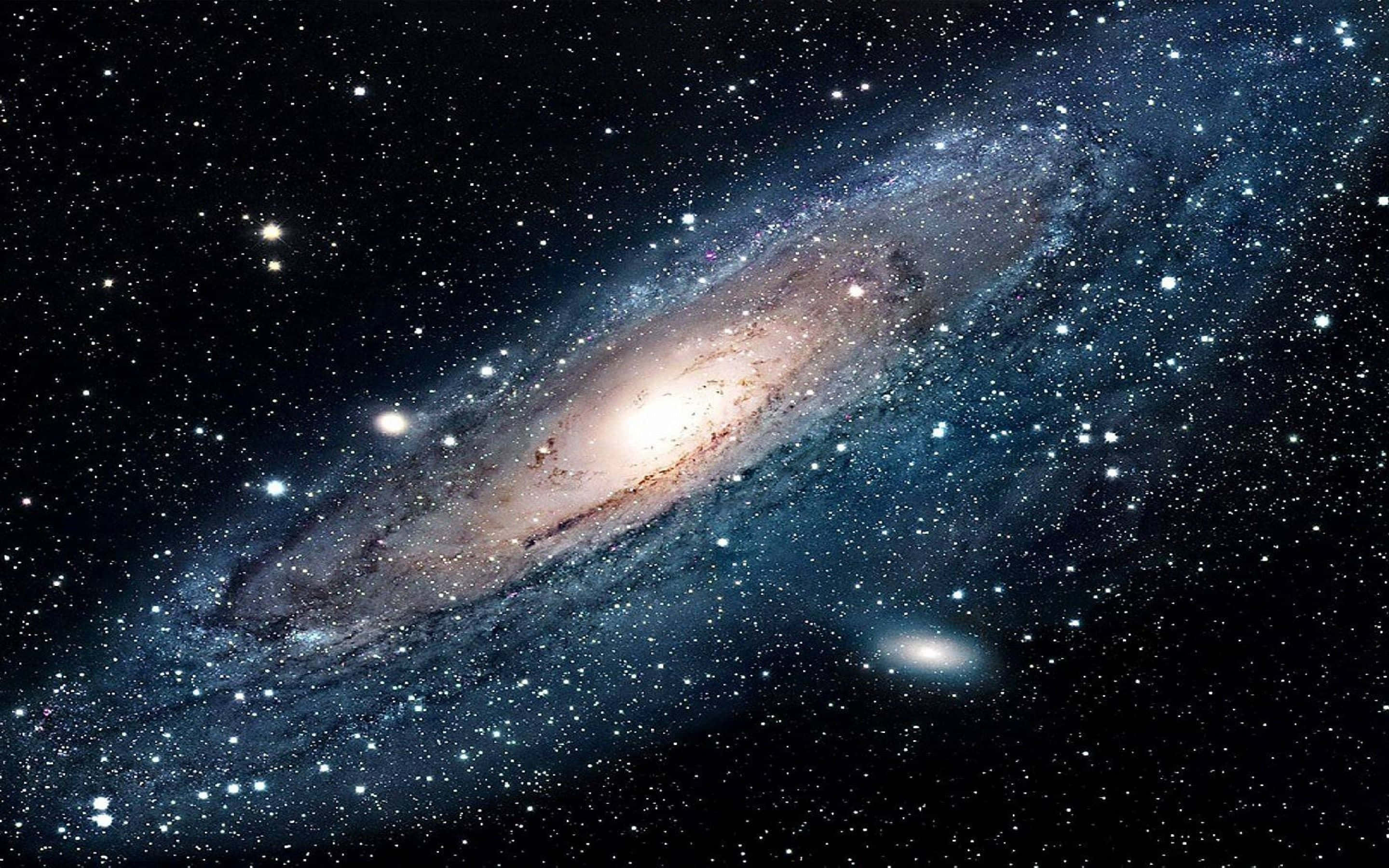 外太空 桌布 壁紙 — 一個令人嘆為觀止的螺旋星系，在佈滿星光的宇宙虛空中閃耀著金色和藍色色調。