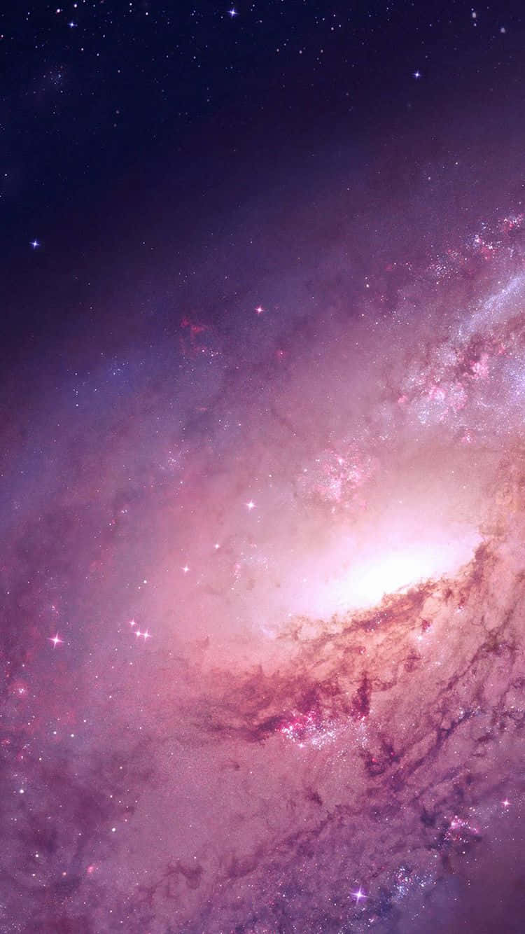 Pink Galaxy 桌布 壁紙 — 一個令人嘆為觀止的螺旋星系，在繁星點點的宇宙背景下閃耀著粉紅色和紫色的星雲。