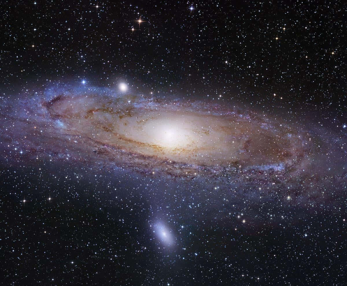 銀河系 桌布 壁紙 — 一個令人嘆為觀止的螺旋星系，在繁星點點的宇宙背景下閃耀著金色和藍色的光芒。