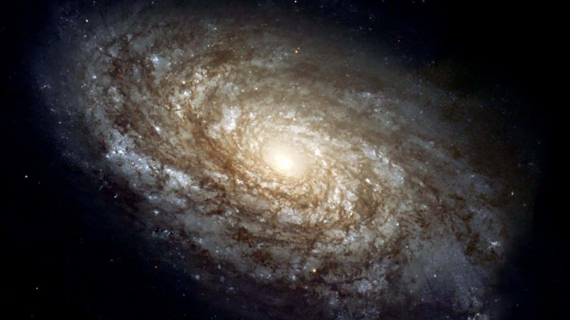 Spiral Galaxy 桌布 壁紙 — 一個令人嘆為觀止的螺旋星系，擁有發光的旋臂和明亮的核心，背景是佈滿星空的黑色虛空。