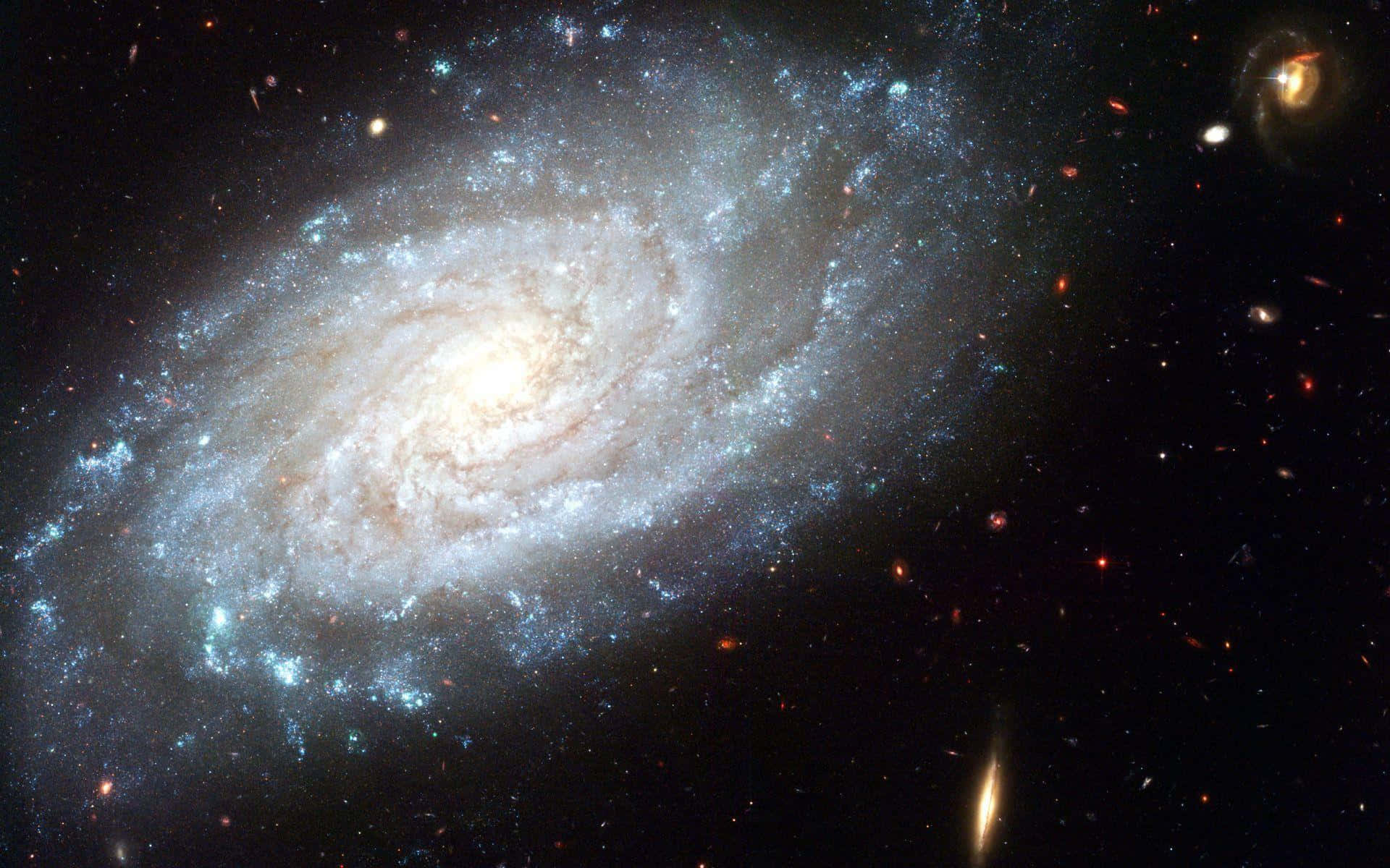 Spiral Galaxy 桌布 壁紙 — 一個令人嘆為觀止的螺旋星系，擁有明亮的藍白色旋臂和發光的核心，主宰著佈滿恆星的宇宙虛空。